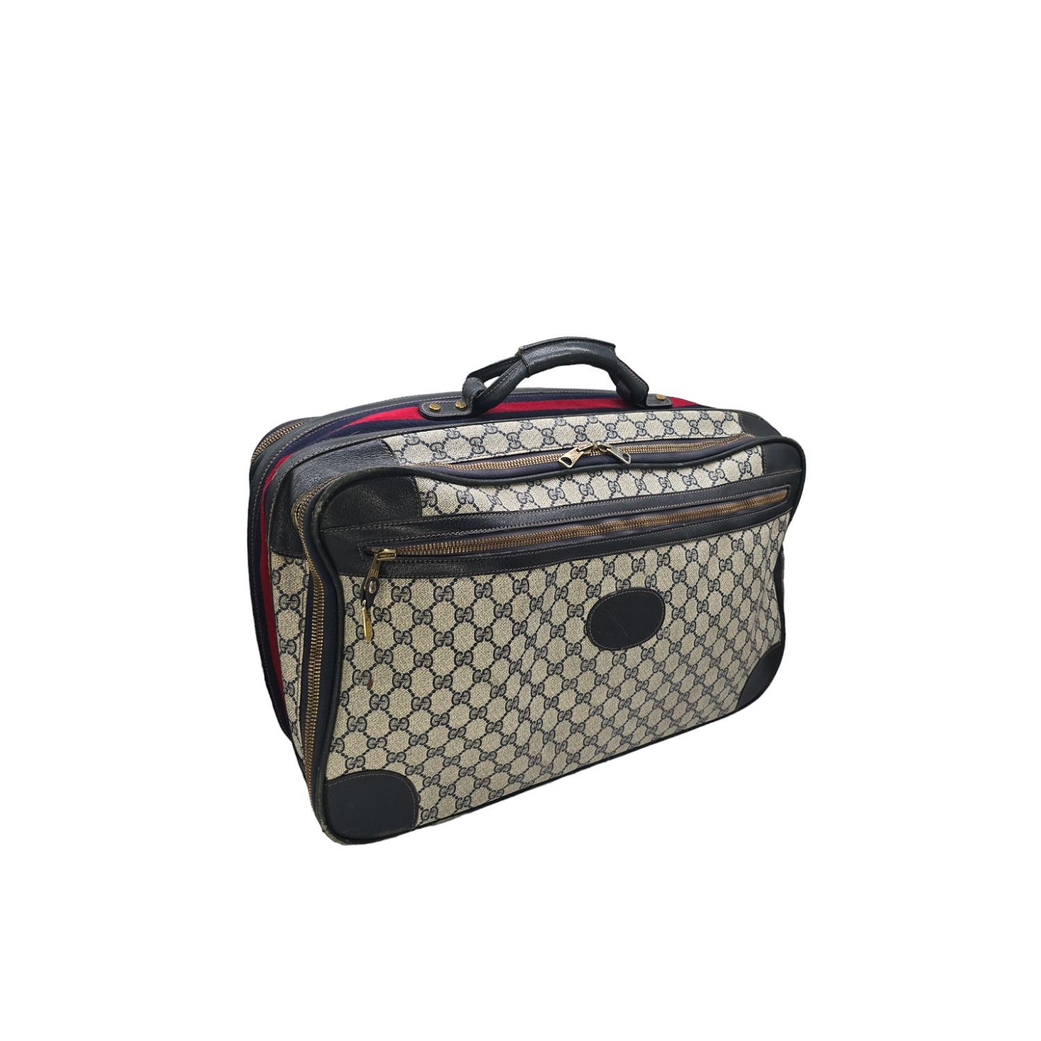 Experience luxury and sophistication while traveling with this vintage Gucci GG Suitcase. Crafted from the iconic GG canvas and navy leather trim, this vintage suitcase exudes elegance. With two spacious compartments and tie straps, this