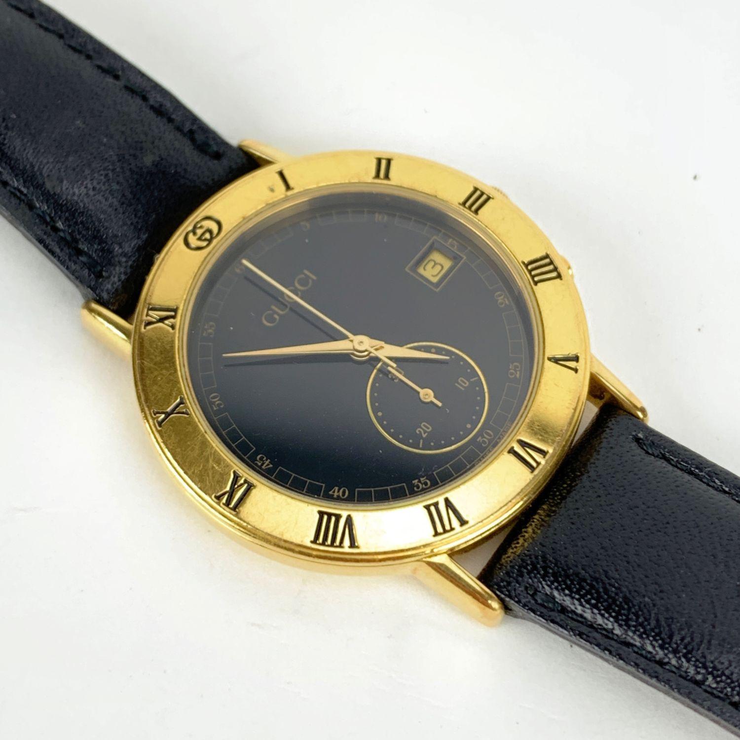 Beautiful vintage wristwatch by GUCCI, Mod. 3400 M. Round gold plated stainless steel case. Black dial. Date indicator at 3. Chrono stop. Swiss Made Quartz Movement. Black leather wrist strap with 7 holes adjustment. GG - GUCCI buckle. 'GUCCI'