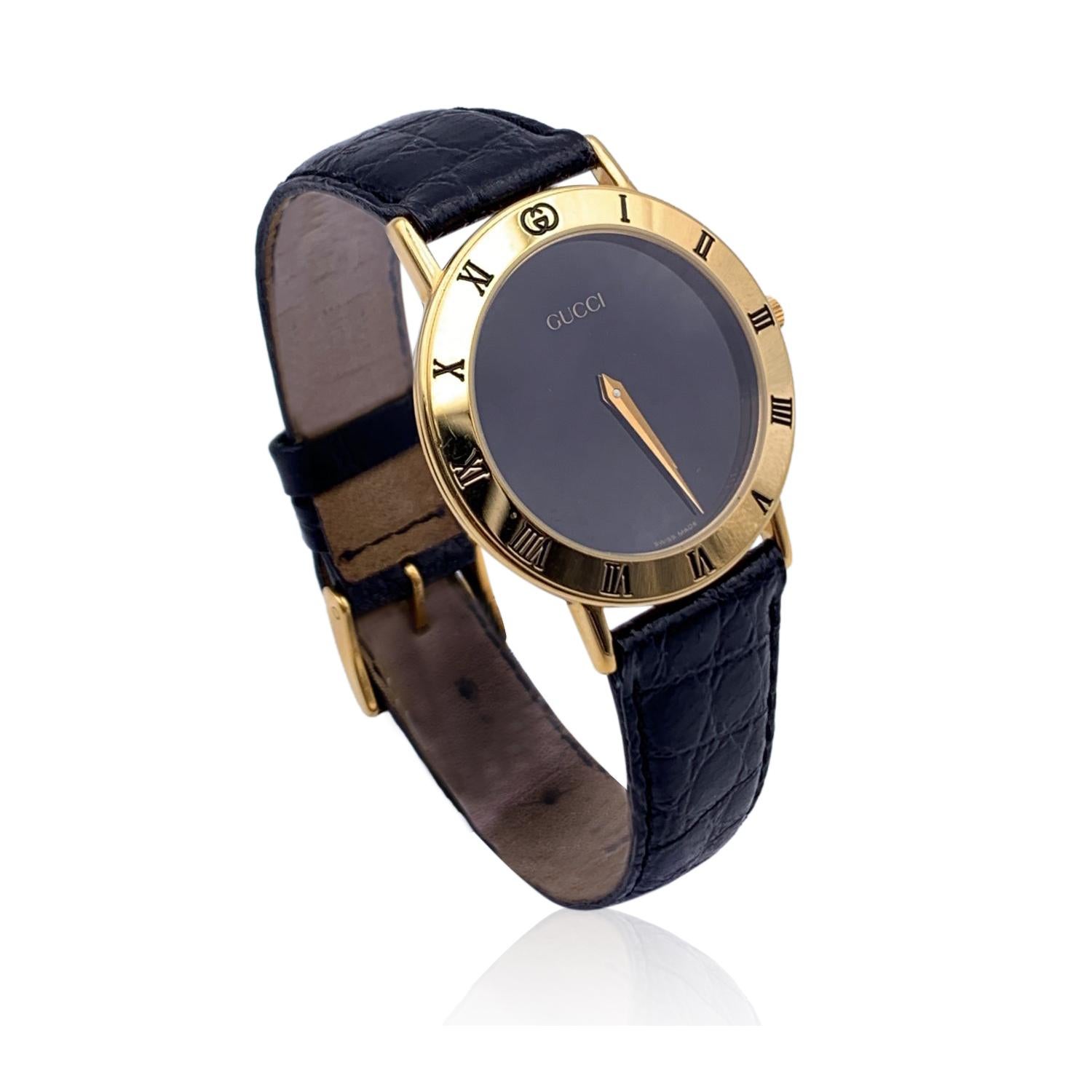 Beautiful vintage wristwatch by GUCCI. Round gold metal stainless steel case. Black dial. Swiss Made Quartz Movement. Black leather wrist strap with 7 holes adjustment. GG - GUCCI buckle. Roman numbers engraved on the bezel. 'GUCCI' lettering on the