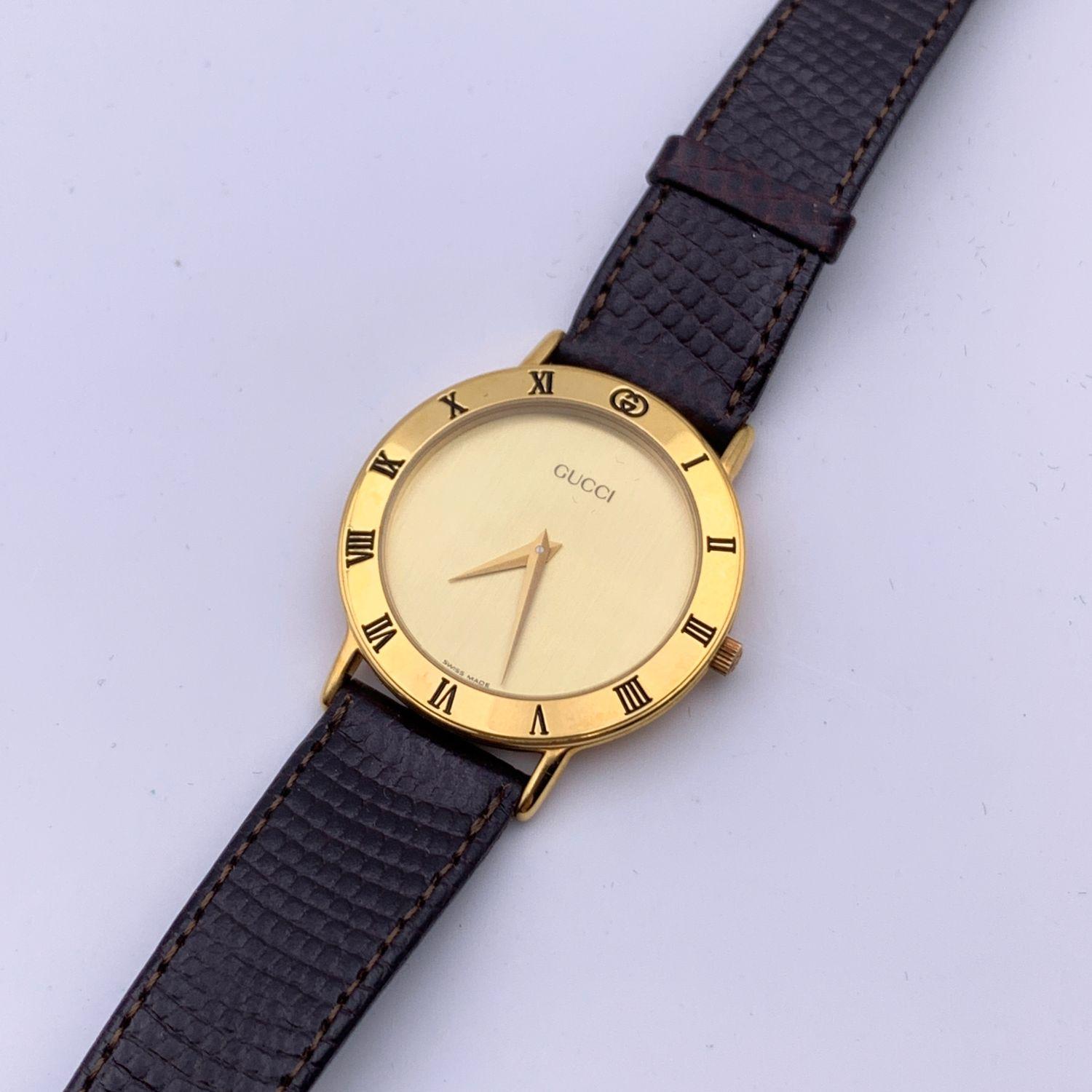 Beautiful vintage wristwatch by GUCCI. Round gold metal stainless steel case. Gold dial. Swiss Made Quartz Movement. Brown leather wrist strap with 6 holes adjustment. GG - GUCCI buckle. Roman numbers engraved on the bezel. 'GUCCI' lettering on the