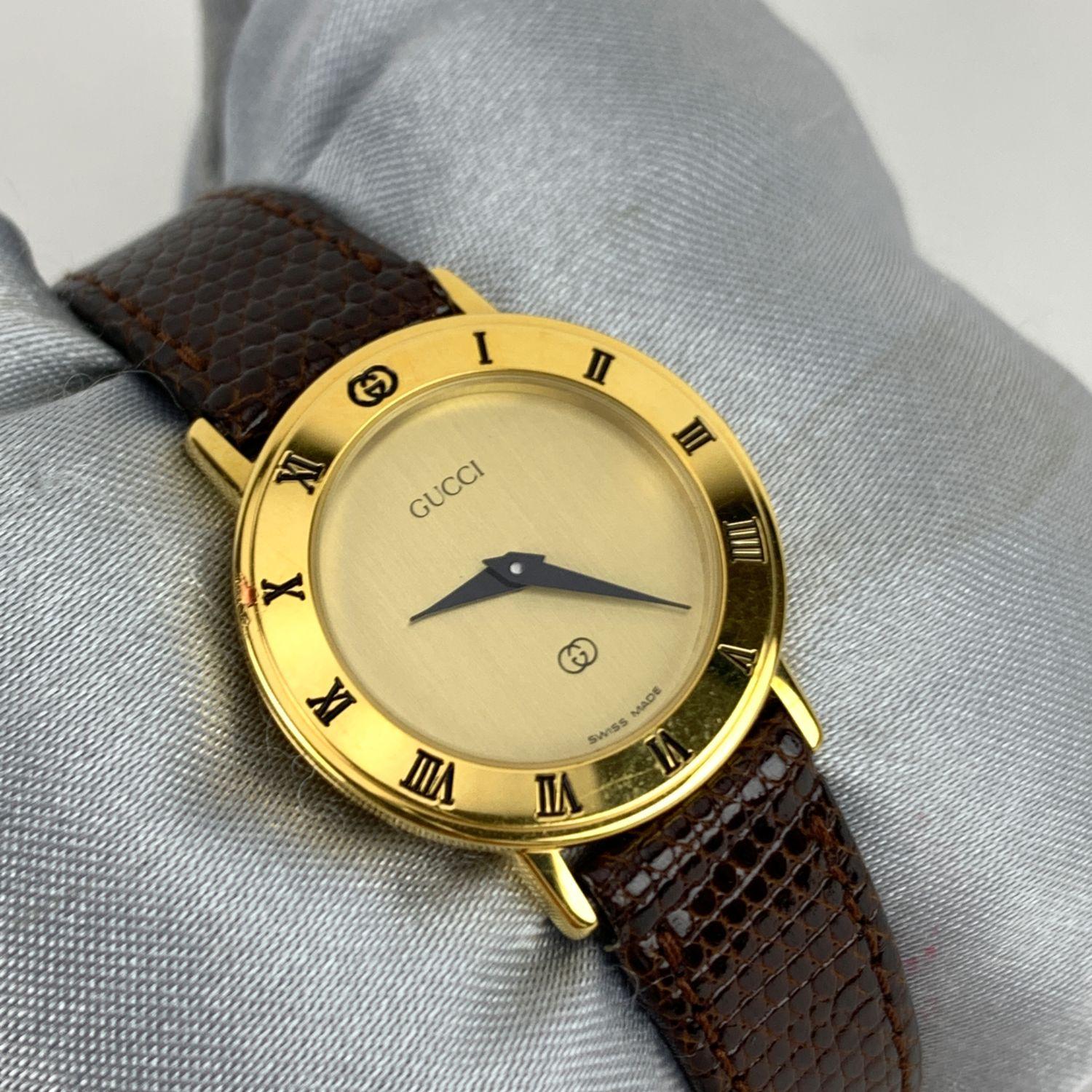 Beautiful vintage wristwatch by GUCCI. Round gold metal stainless steel case. Beige dial. Swiss Made Quartz Movement. Brown leather wrist strap with 7 holes adjustment. GG - GUCCI buckle. Roman numbers engraved on the bezel. 'GUCCI' lettering on the
