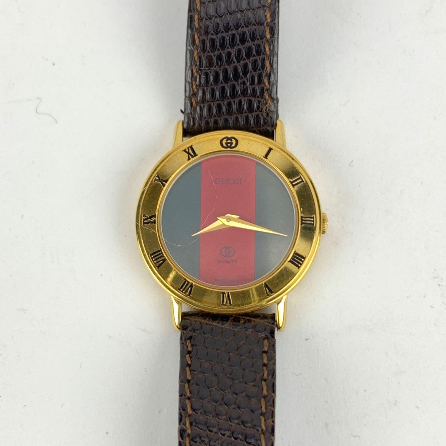 Beautiful vintage wristwatch by GUCCI. Round gold metal stainless steel case. Gree/Red/Green dial. Swiss Made Quartz Movement. Brown leather wrist strap with 7 holes adjustment. GG - GUCCI buckle. Roman numbers engraved on the bezel. 'GUCCI'