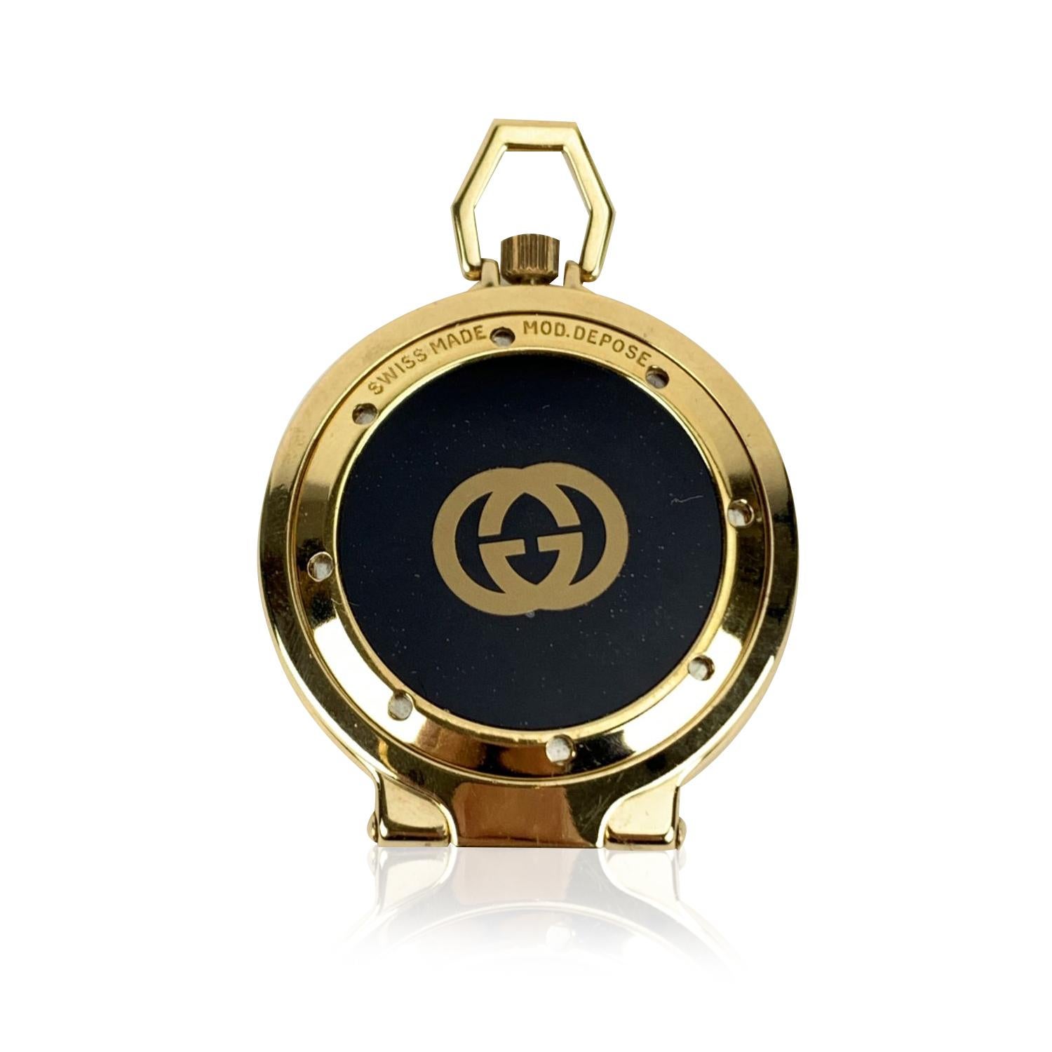 Rare vintage Gucci gold-tone stainless steel 'World cities' alarm travel clock. From the '80s. Round-design and pocket size. Rear folding bezel on the back allows you to keep it standing. It features black dial, date indicator at 3, roman numbers