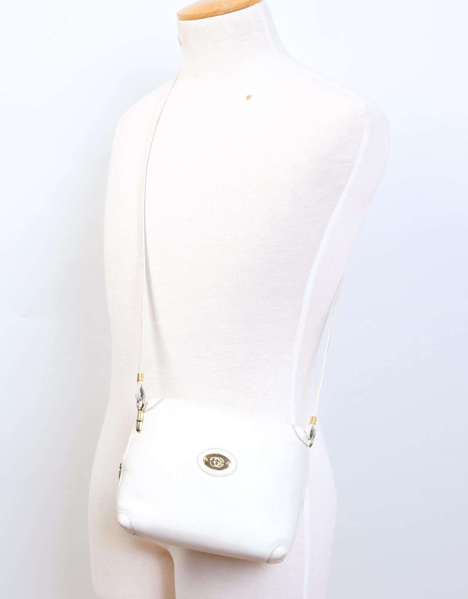 Diese Vintage-Umhängetasche von Gucci ist aus weißem Leder gefertigt und verfügt über eine goldfarbene, ineinandergreifende GG-Plakette, einen langen Schulterriemen, einen Reißverschluss an der Oberseite und ein Innenfutter aus Wildleder.  Vintage