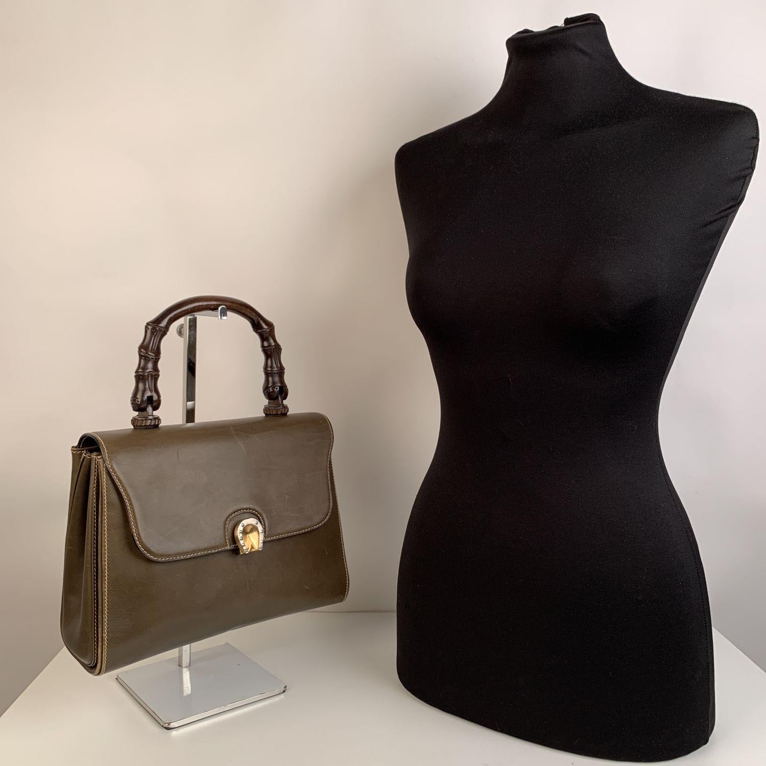 Beautiful Gucci vintage handbag, crafted in military green leather, with wood bamboo-shaped handle. Flap with clasp closure. Horseshoe clasp in silver and gold metal. Beige lining. 1 side zip pocket and 2 side open pockets inside. 'Gucci - Made in