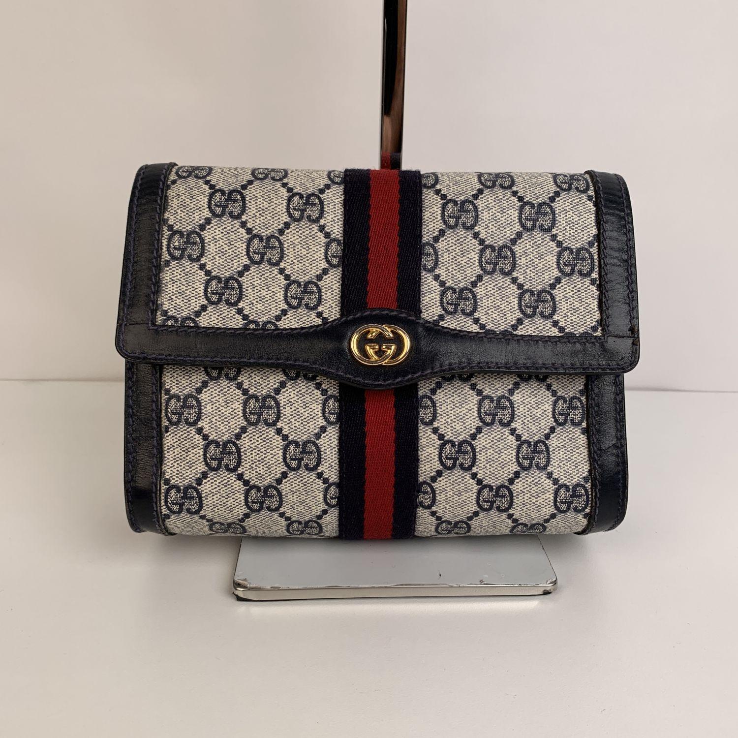 Gucci Vintage flap cosmetic bag with Stripes. Blue Monogram Canvas with Genuine Leather trim. Blue/Red/Blue stripes around the bag. Gold metal GG - GUCCI logo on the front. Flap with button closure on the front. Waterproof lining. 