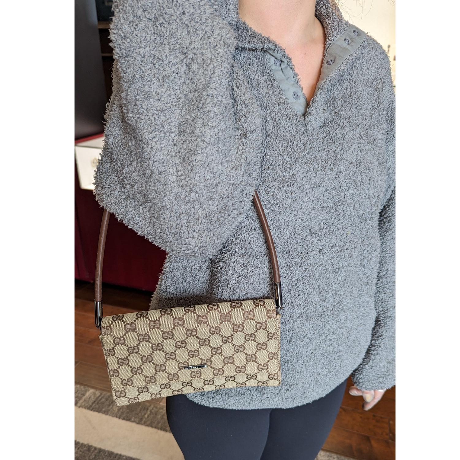 This chic handbag is finely crafted of Gucci GG monogram fabric canvas in beige with brown. The shoulder bag features a brown leather strap, leather piping, and silver-tone hardware. The flap opens to a partitioned brown fabric interior.

Designer: