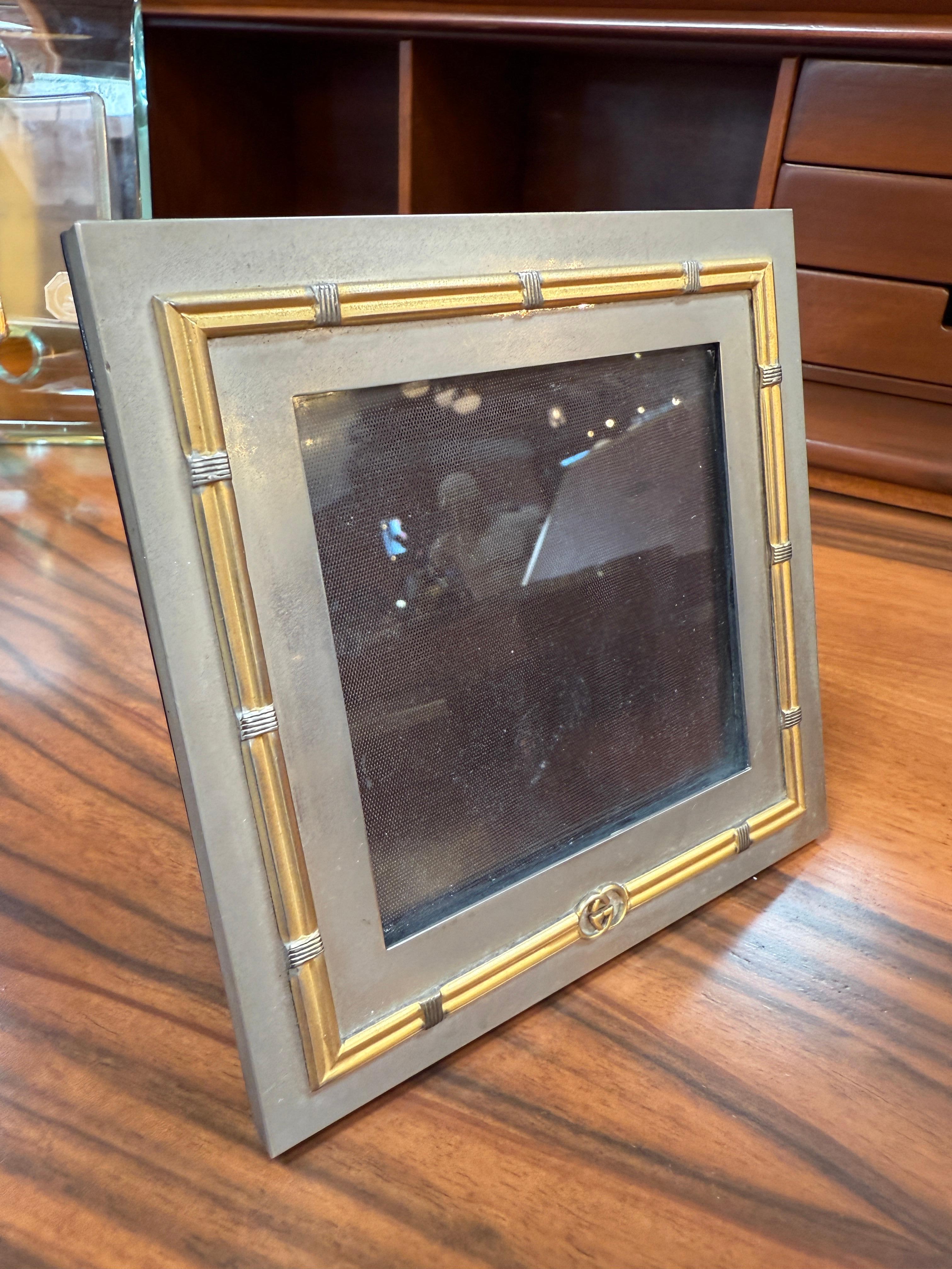 Dieser elegante Vintage-Fotorahmen von Gucci zeichnet sich durch ein raffiniertes Design aus, das mattes, silberfarbenes Metall mit goldenen Akzenten im Bambus-Stil verbindet. Die Ecken und Querschnitte sind mit feinen Details versehen, während die