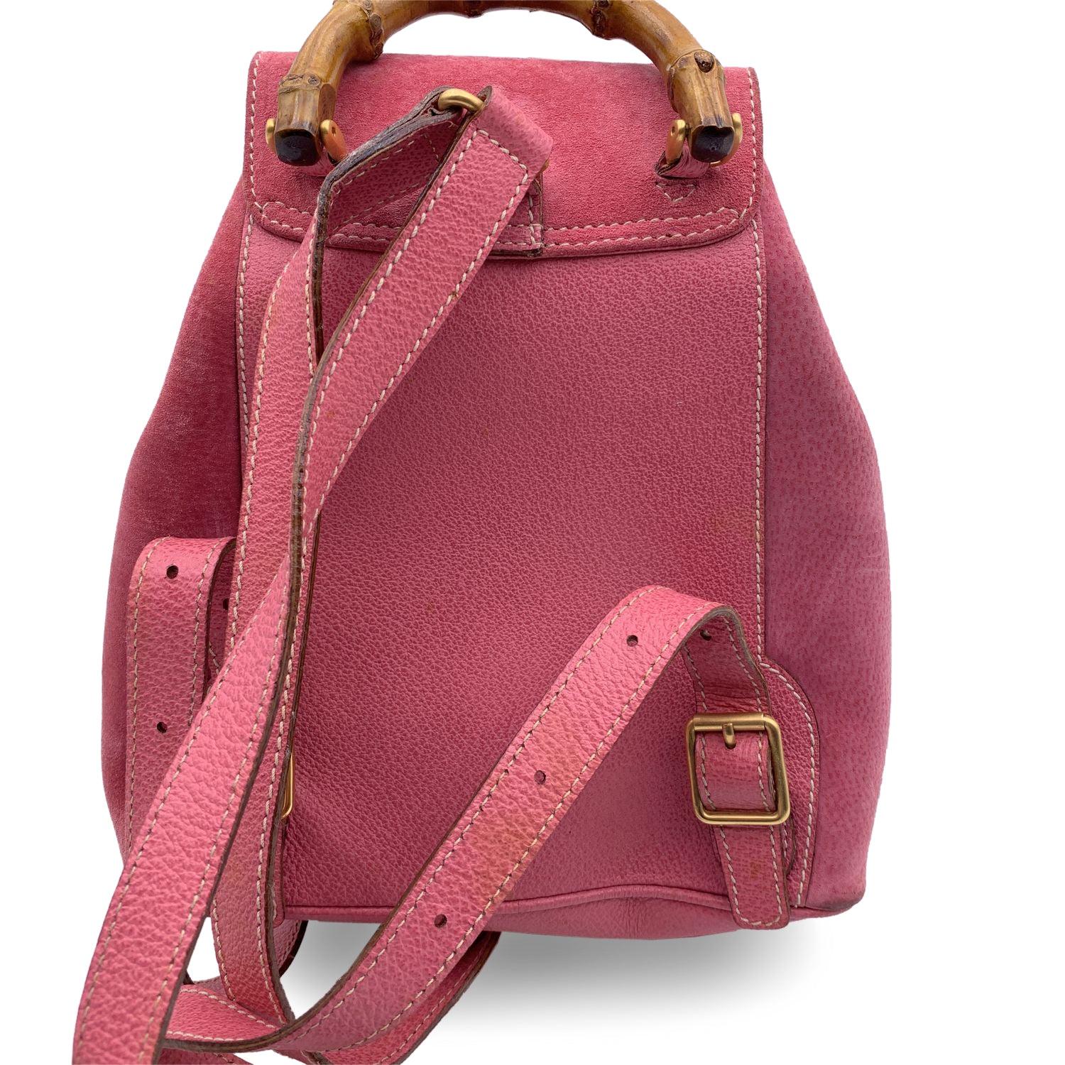 Vintage small backpack by Gucci, crafted in pink suede and leather. It features Bamboo handle and and knob. 1 front pocket with twist lock closure. Flap closure and drawstring top opening. Gold metal hardware. Internal diamond lining. 1 side zip