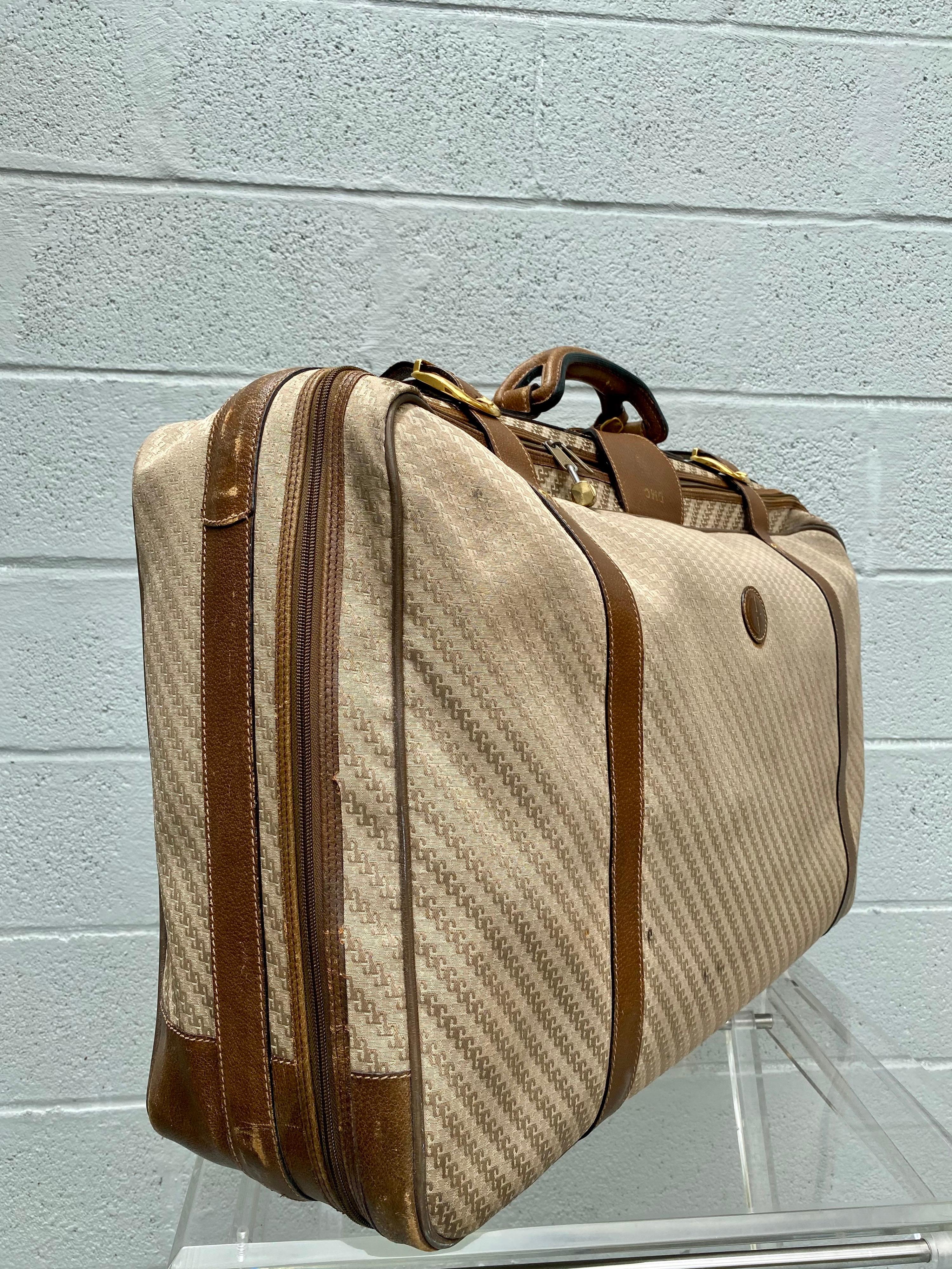 The classic stylish Gucci luggage is crafted of signature GG monogram on canvas. Extremely rare vintage luggage from the 1970's. The bag features leather trim, rolled leather top handle, and flap lock closure. The zippers open to a spacious fabric