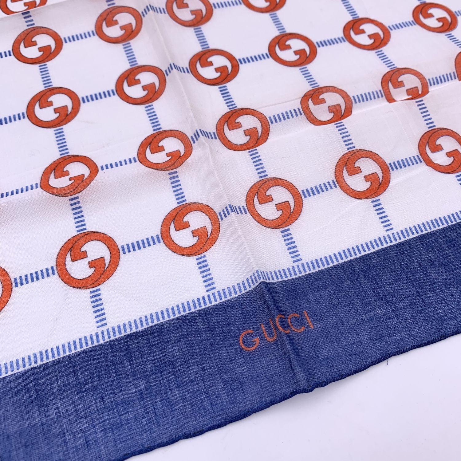 Vintage neck scarf by GUCCI. 100% Cotton. Red/orange GG logo pattern with blue borders. 'Gucci' signature printed on the lower center border. Approx. Measurements: 16.5 x 16.5 inches - 42 x 42 cm Details MATERIAL: Cotton COLOR: Blue MODEL: n.a.