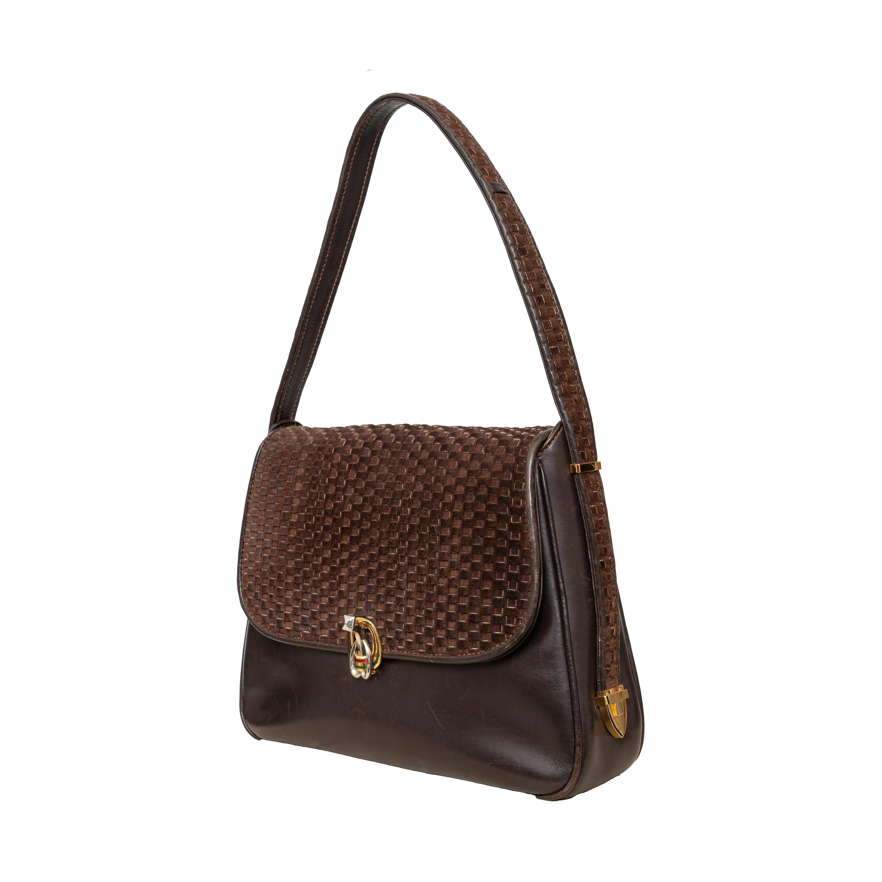 Vintage 80s Gucci shoulder bag in brown leather with velvet patterned accent, featuring a unique closure and iconic red and green Gucci emblem for a touch of luxury.
 Inclusion: dust bag.
 Remarks: There are many scratches and a storage smell.  
