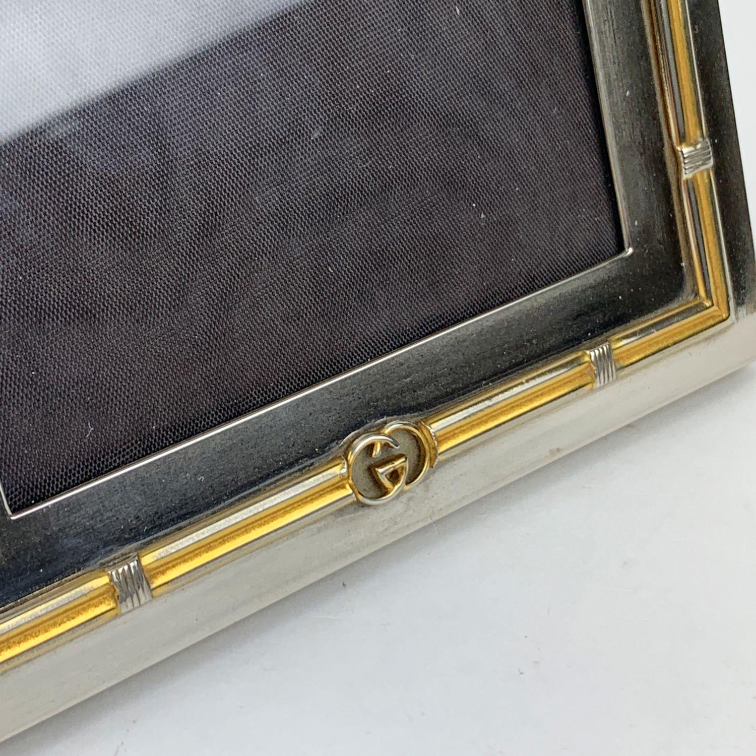 Vintage silver metal desk photo frame by Gucci. GG - GUCCI logo on the front. Square-shaped. Clear glass on the front and Wood on the back. ' Gucci - Italy' engraved on the upper border. Measurements (HxL):5.5 x 5.5 inches -14 x 14 cm. For approx 4