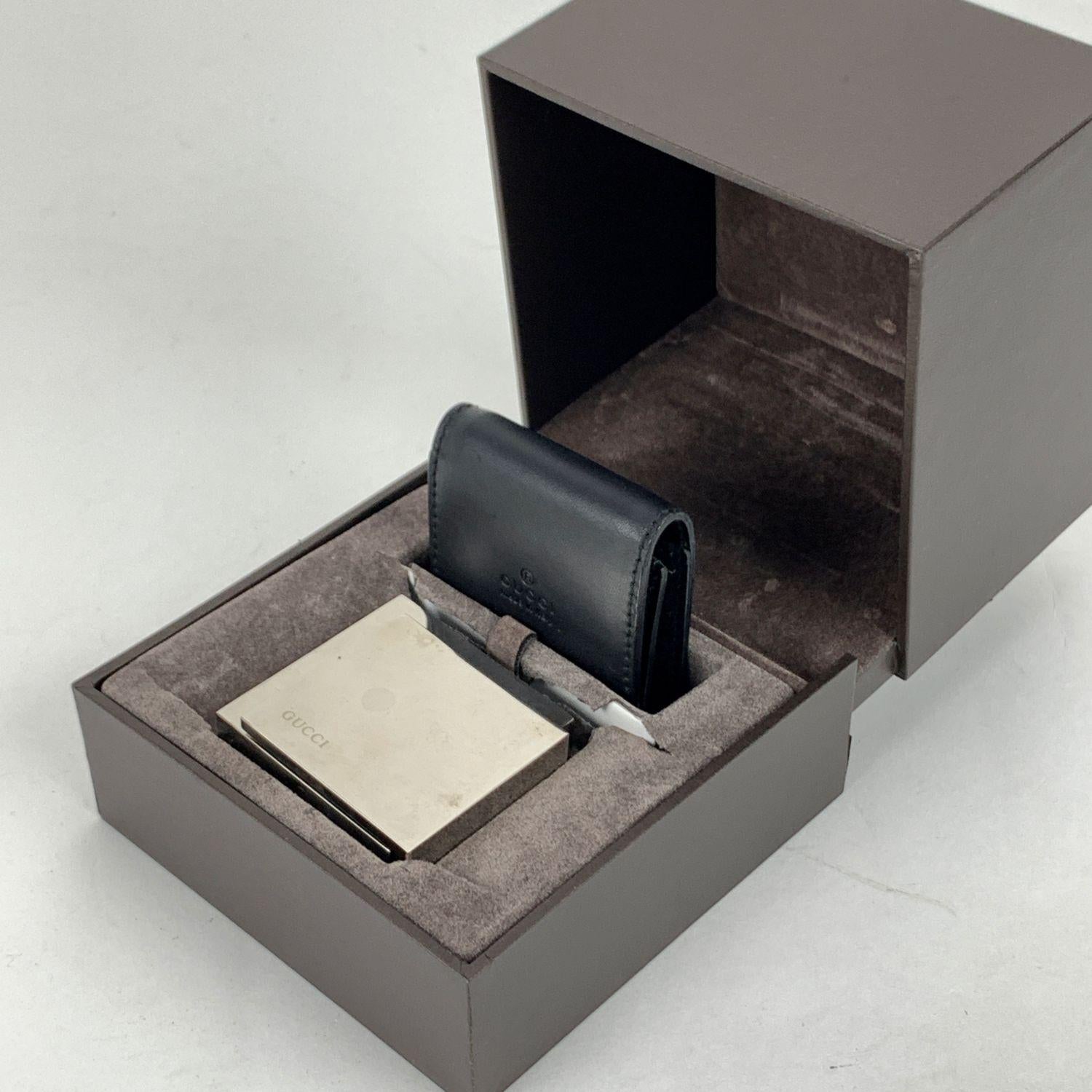 Gucci stainless steel alarm travel clock, mod. 0840. The front cover opens and allows you to keep it standing. Squared-design and pocket size. It features luminous hands and Alarm indicator. Swiss made quartz movement. Measurements: 1.75 x 2 inches