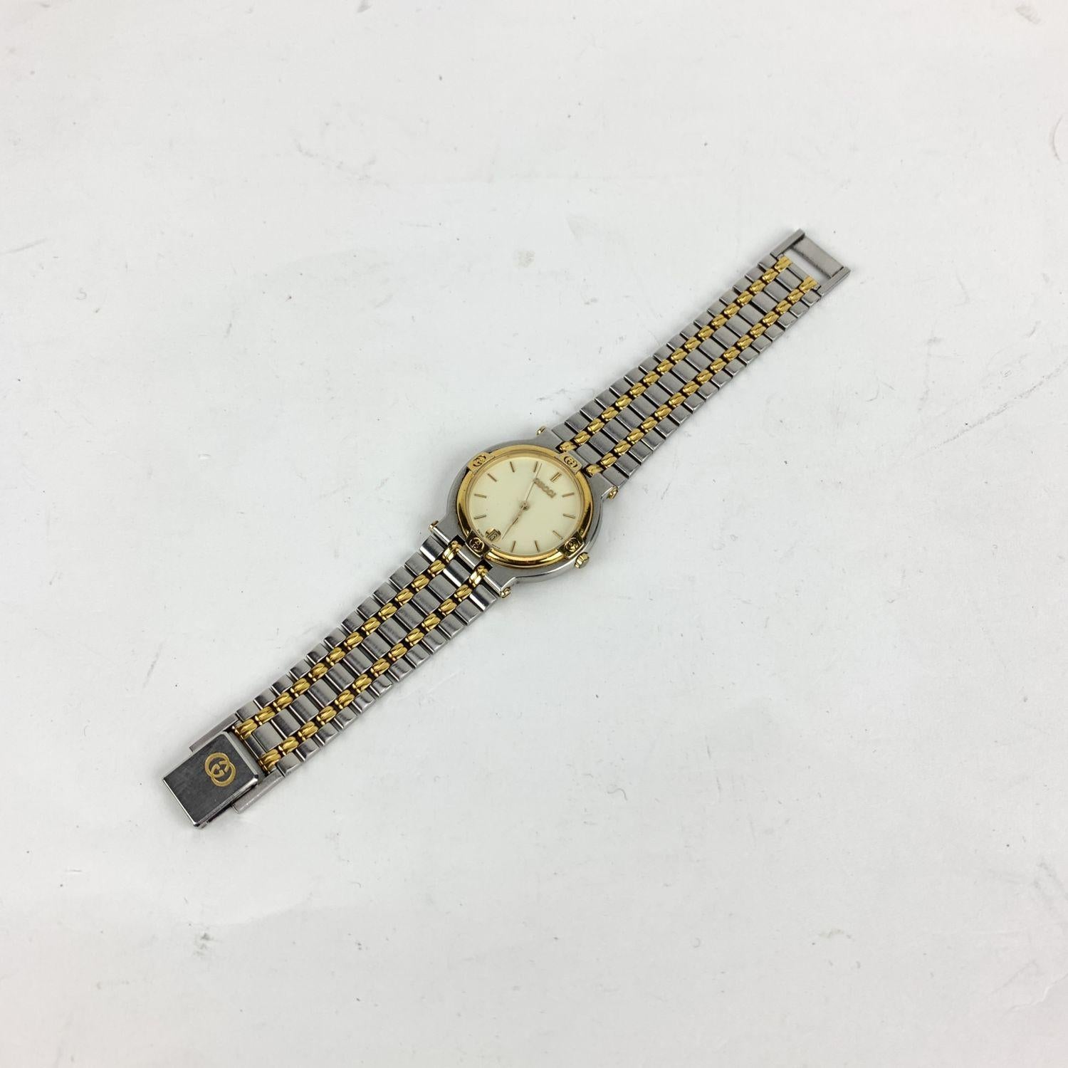 Gucci Mod. '9000 M' stainless steel wrist watch. Stainless steel round case with gold plated bezel detailed with GG logos. White dial with gold hands and markers. Sapphire crystal. Date indicator. Swiss quartz movement. Stainless steel and gold