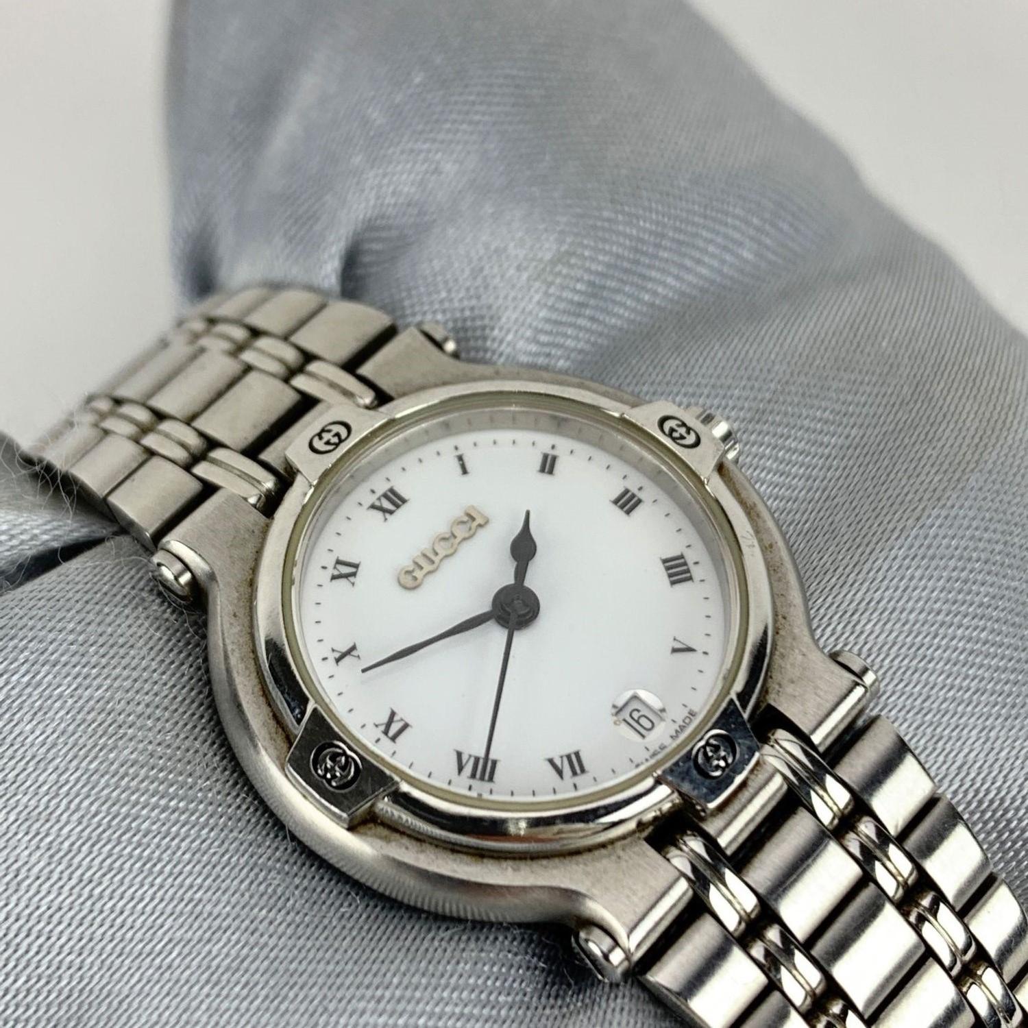 Gucci stainless steel wrist watch, mod. 9100 L. Stainless steel case. White Dial. Date at 6 o'clock. Sapphire crystal. Swiss Made. Quartz movement. Gucci written on face. Gucci crest on the reverse of the case. GG logo engraved on the clasp. Water
