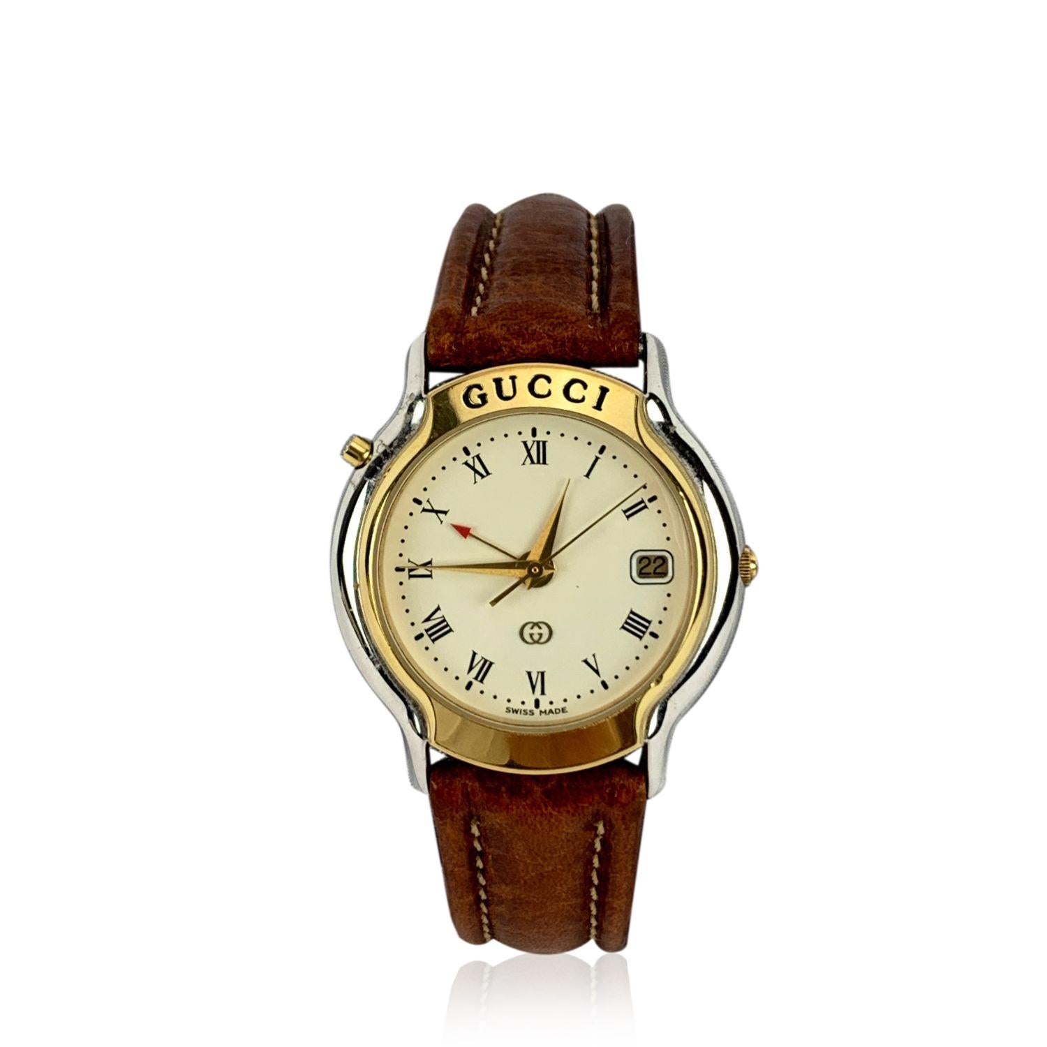 Beautiful vintage wristwatch by GUCCI, mod. 8200 M. Round gold metal and silver tone stainless steel case.Gucci signature on the bezel. White dial. Date indicator at 3 'o clock. Swiss Made Quartz Movement. Brown leather wrist strap with 6 holes