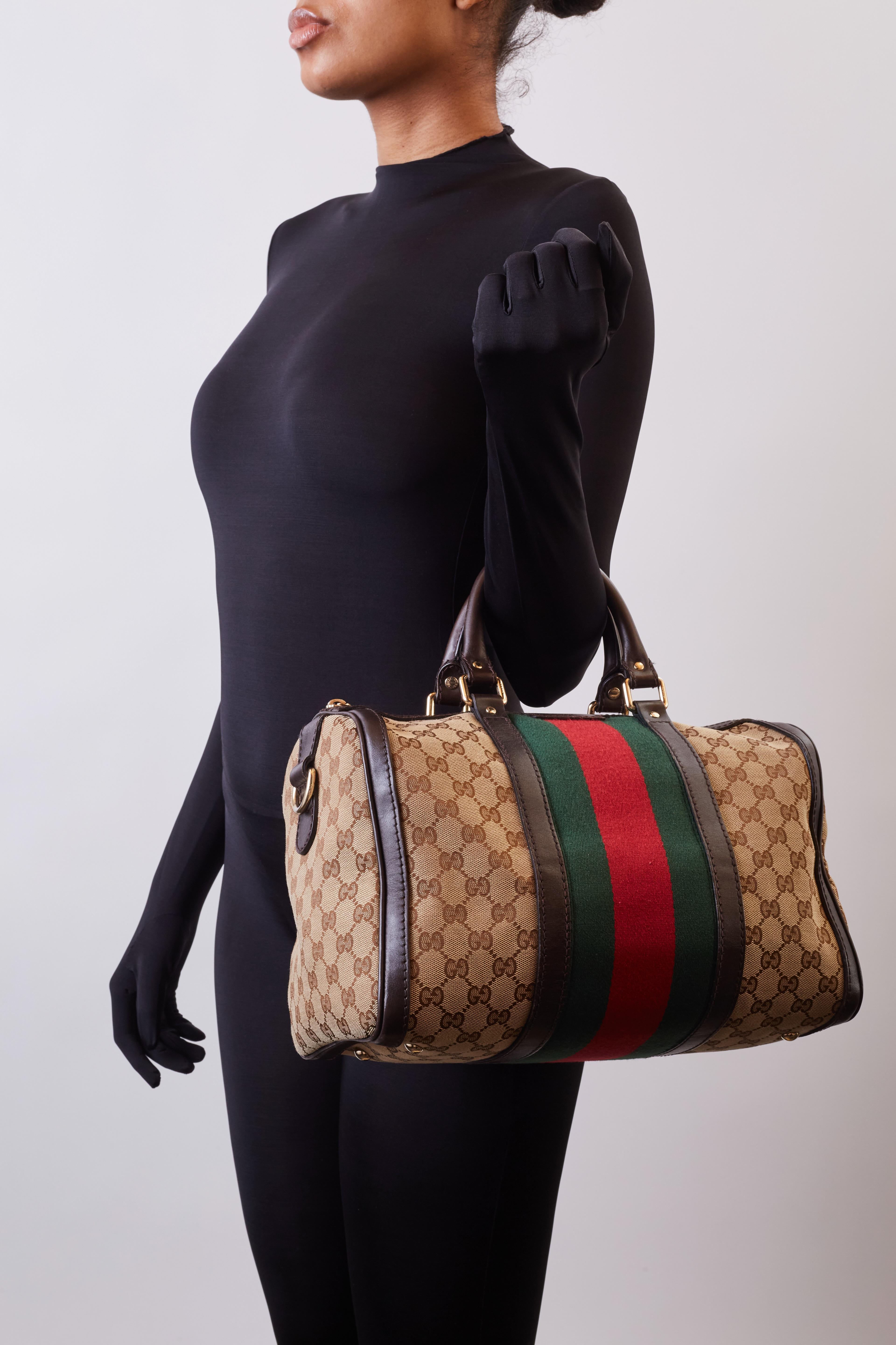 This vintage style Boston bag is made of Gucci GG monogram canvas. The bag features dark ebony leather finishes throughout including dual rolled leather top handles, trim, details and an optional shoulder strap. The bag also features a central green