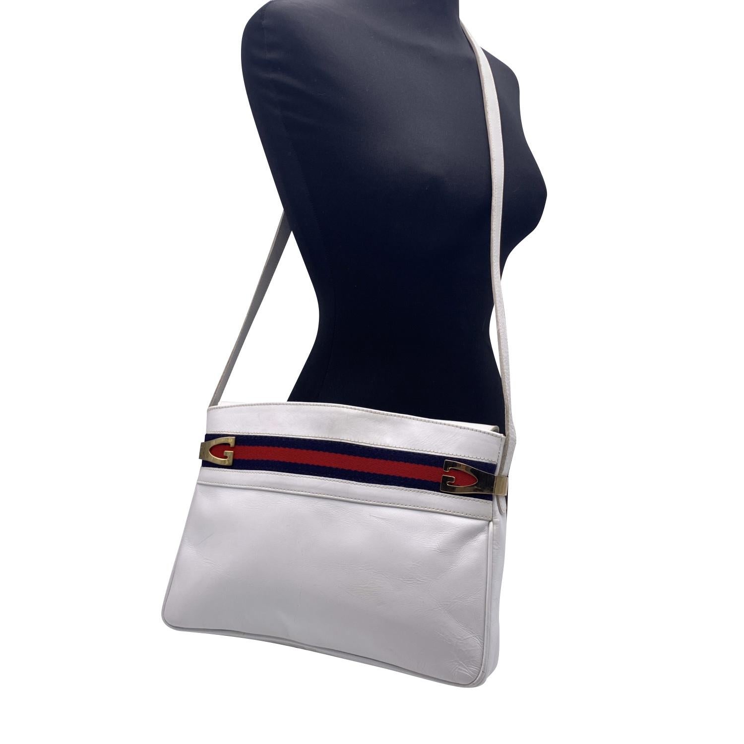 Vintage Gucci shoulder bag crafted in white leather. Blue/Red/Blue stripes on the upper part of the bag. Gold metal G-shaped hardware on top. Magnetic button closure. White leather interior. 1 side zip pocket inside. 'Gucci Italy' crest embossed