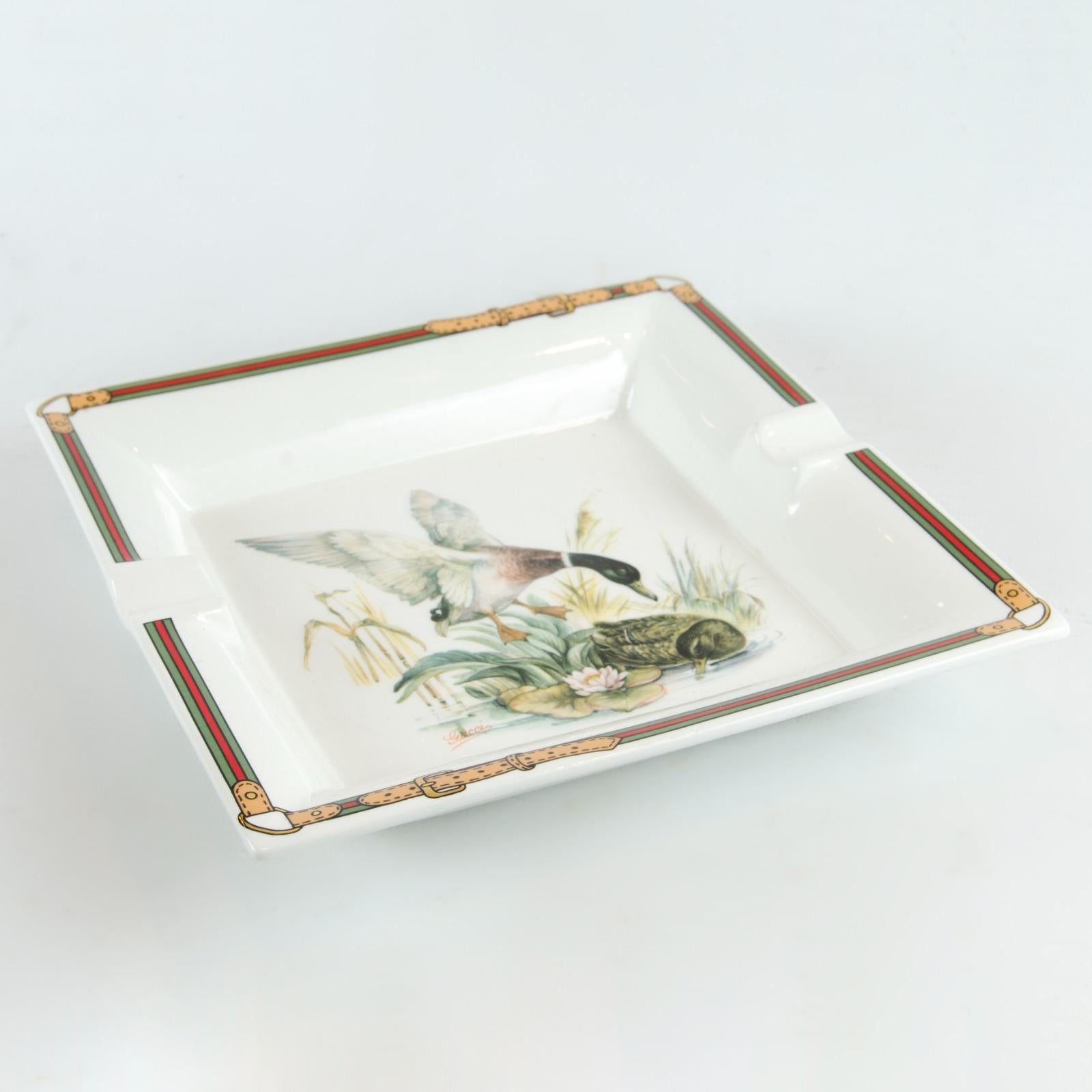 - White Porcelain
- Green/red/green belts detailing along the borders
- Ducks theme design in the center
- 'GUCCI - Made in Italy' embossed on the base of the ashtray
- Square-Shaped
- MEASUREMENTS (inches/cms): 7 1/2 x 7 1/2 inches - 19 x 19