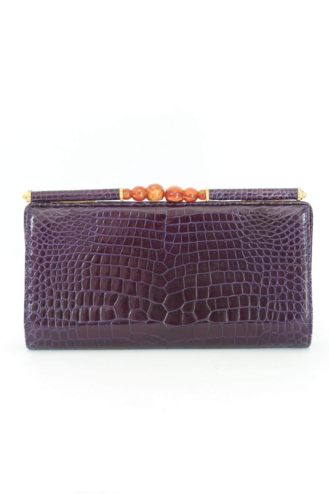 This elegant Gucci clutch bag is a rare vintage piece from the 1970s. Made from genuine purple crocodile leather, it features jeweled handles with Swarovski for a truly luxurious look. Clip closure, internally lined in purple leather with two small