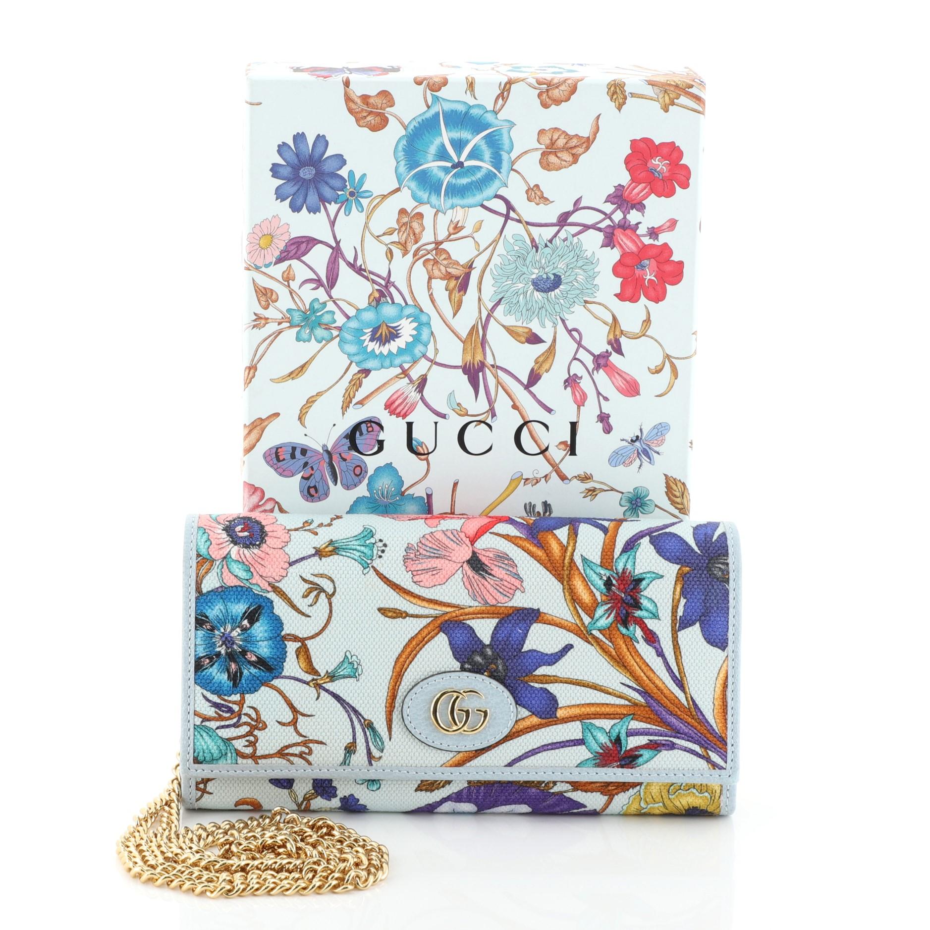 This Gucci Wallet on Chain Flora Canvas, crafted in blue printed canvas, features chain-link strap, GG logo at front Floral print and gold-tone hardware. It opens to a blue leather and fabric interior with multiple card slots and zip pocket.