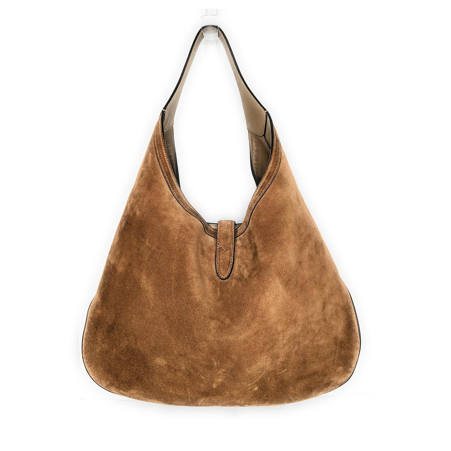 Cozy up to a quintessential Gucci look with this Large Brown Suede Web Soft Jackie Hobo! Red-and-green webbing stripe down the front. Brushed gold-tone piston to secure the top. Inside you’ll find a zipped leather pouch on a leash nestled within the