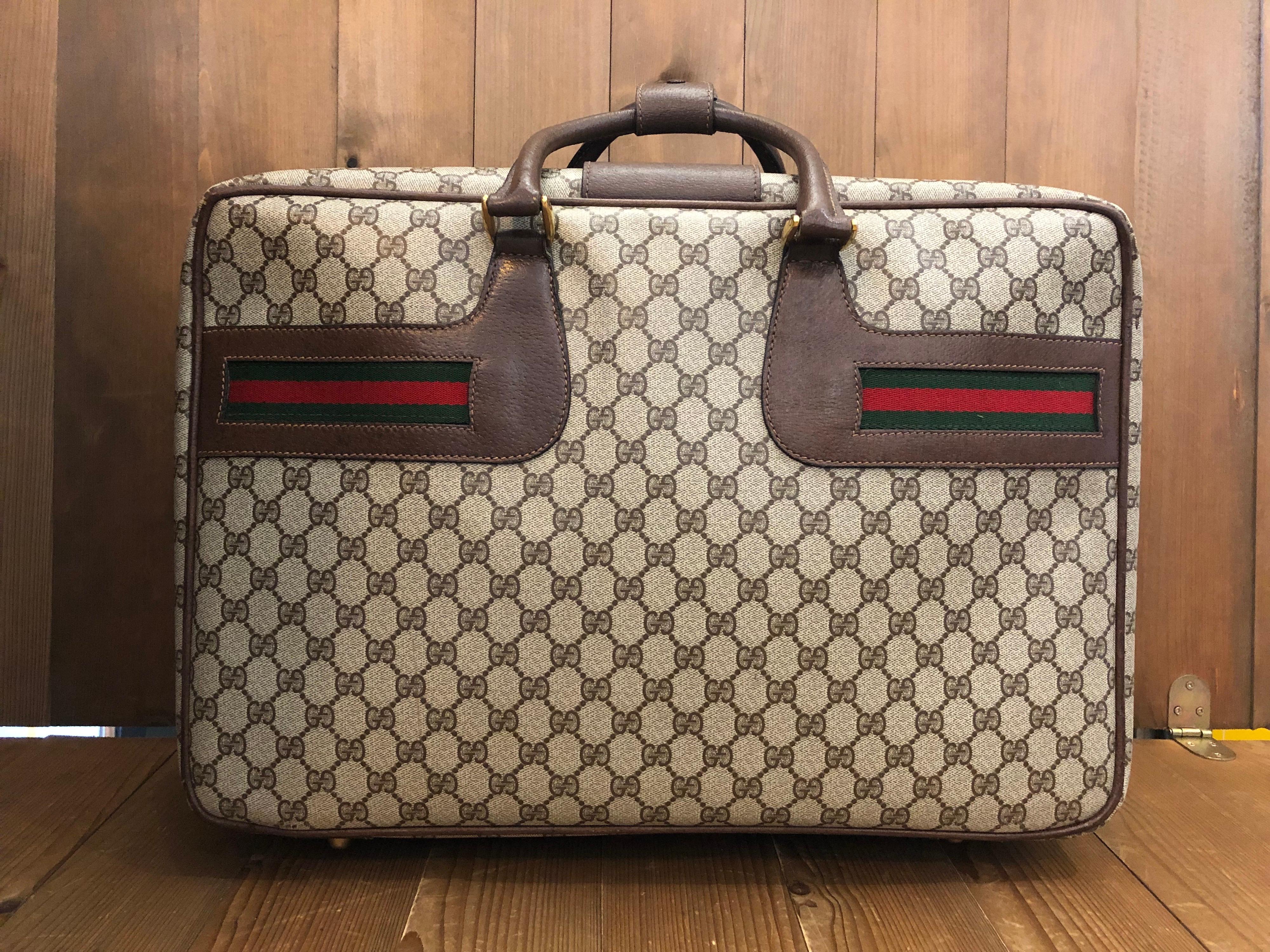 1970s Gucci Web softsided suitcase 50 in brown GG monogram coated canvas and leather and decorated with iconic red/green band. Made in Italy. Measures 19.25 x 13 x 6.25 inches. 

Condition - Minor signs of wear. Generally in good