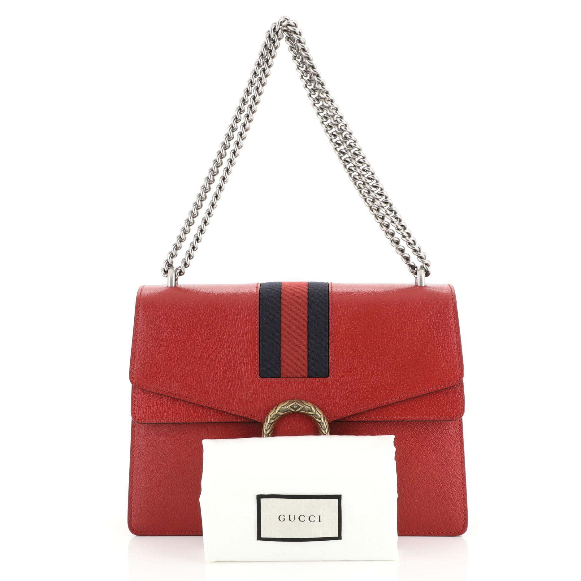 This Gucci Web Dionysus Bag Leather Medium, crafted from red leather, features a chain link strap, textured tiger head spur detail on its flap, signature web detailing, and aged gold and aged silver-tone hardware. Its hidden push-pin closure opens