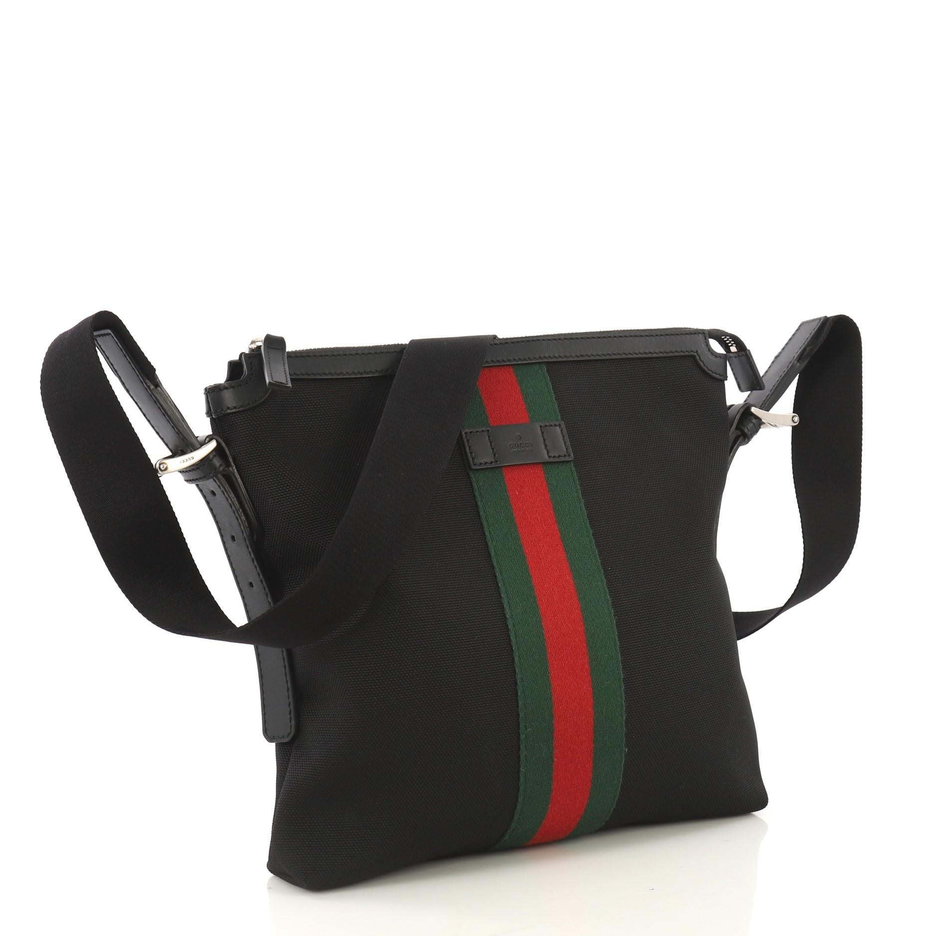 This Gucci Web Messenger Bag Techno Canvas Medium, crafted from black techno canvas, features an adjustable canvas shoulder strap, red and green web detail, and silver-tone hardware. Its zip closure opens to a black nylon interior with side zip and