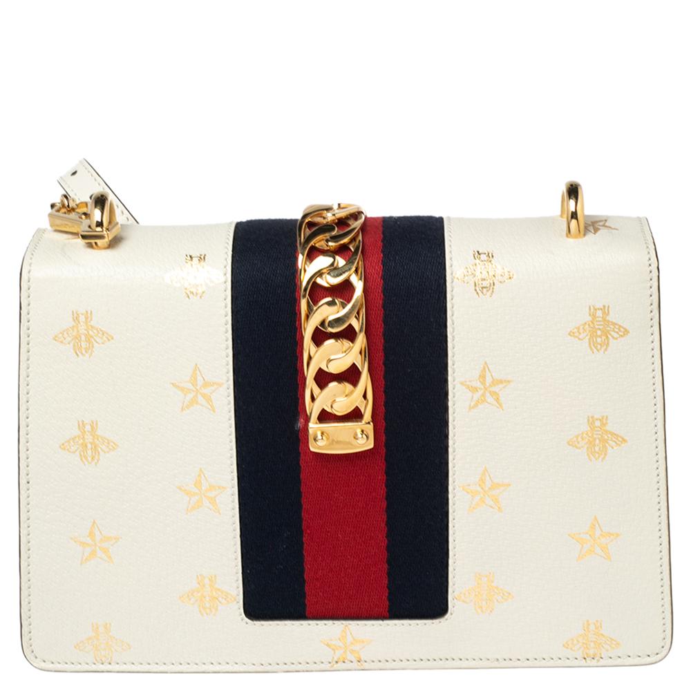 This Sylvie bag from Gucci emerges as an everlasting icon of opulence and elegance with its brilliantly designed structure. It has been luxuriously crafted from white leather, which is augmented by a Bee-Star print throughout. The iconic Web strap