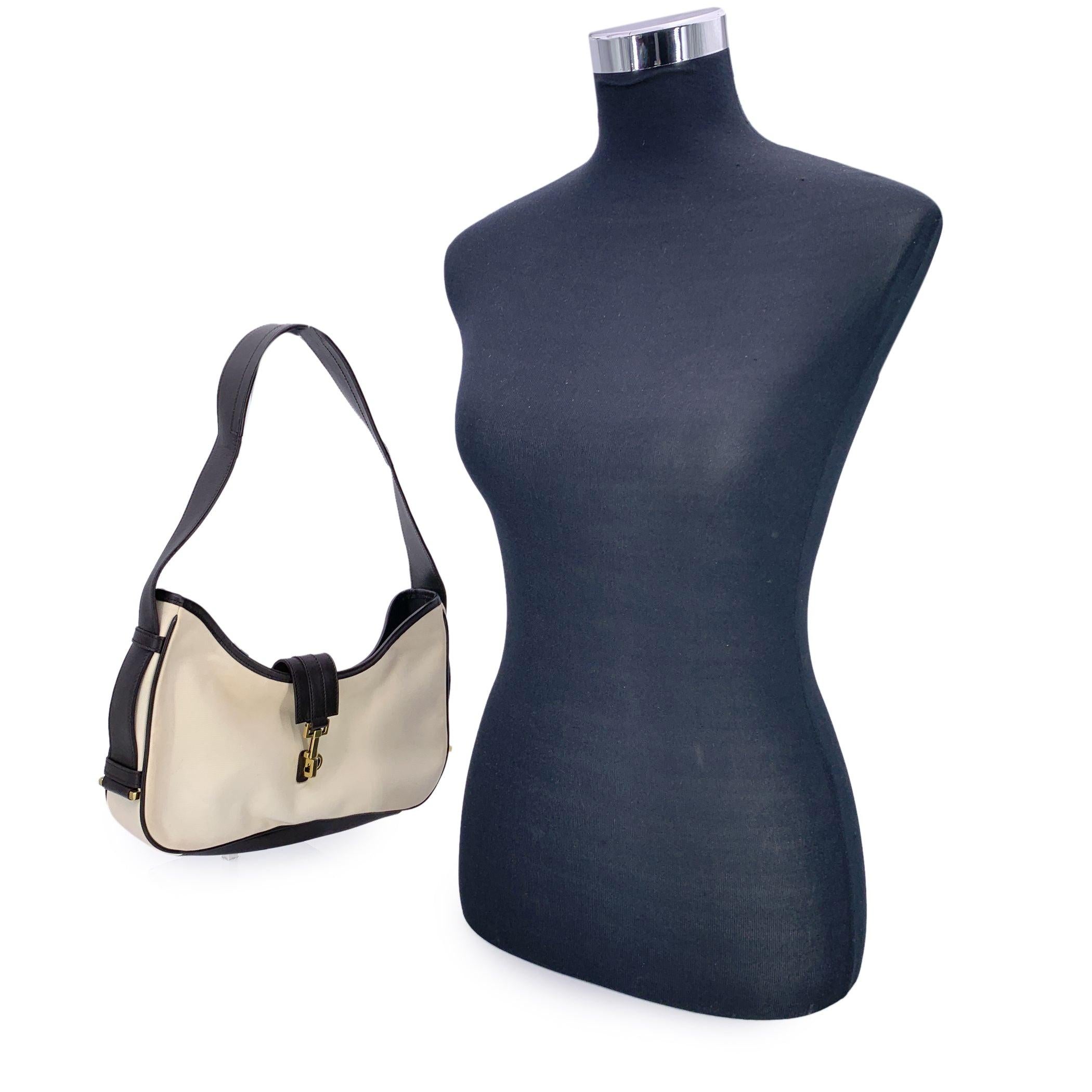 For those who love vintage charm with a touch of modern edge, this Gucci white canvas hobo bag bag is a standout piece that speaks to effortless Italian sophistication. Framed by rich dark brown leather trim and accented with gleaming gold hardware,