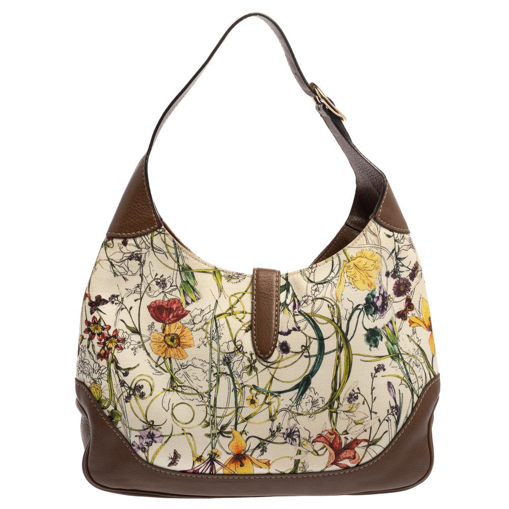 Gucci bietet seit jeher eine Reihe von Kult-Accessoires an:: so wie diese Jackie Hobo:: die 1958 als Hommage an Jacqueline Kennedy Onassis entworfen wurde. Das Segeltuch ist mit bunten Blüten bedruckt:: während die kontrastierende Ledereinfassung