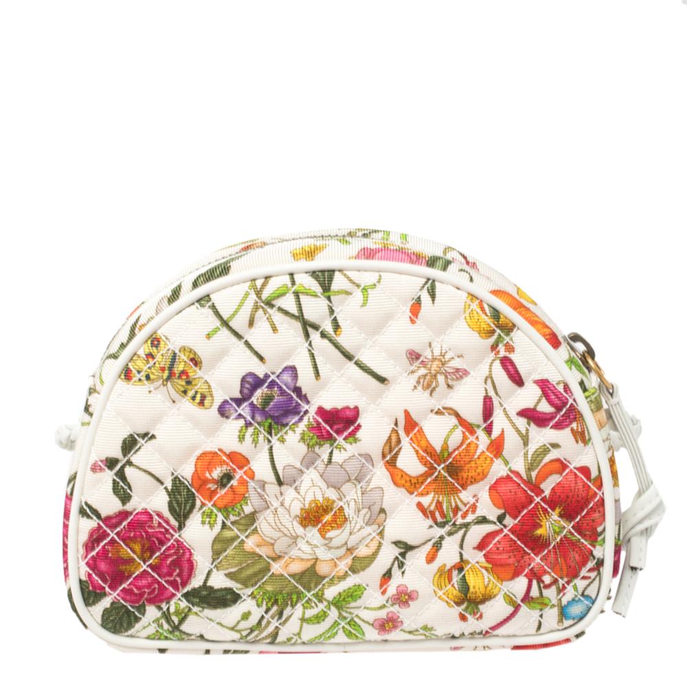 This stylish crossbody bag is crafted of canvas in a quilt pattern. The creation features a braided strap and the GG logo and Horsebit detail in gold-tone and silver-tone. It features a vibrant floral pattern atop a white background. The bag opens