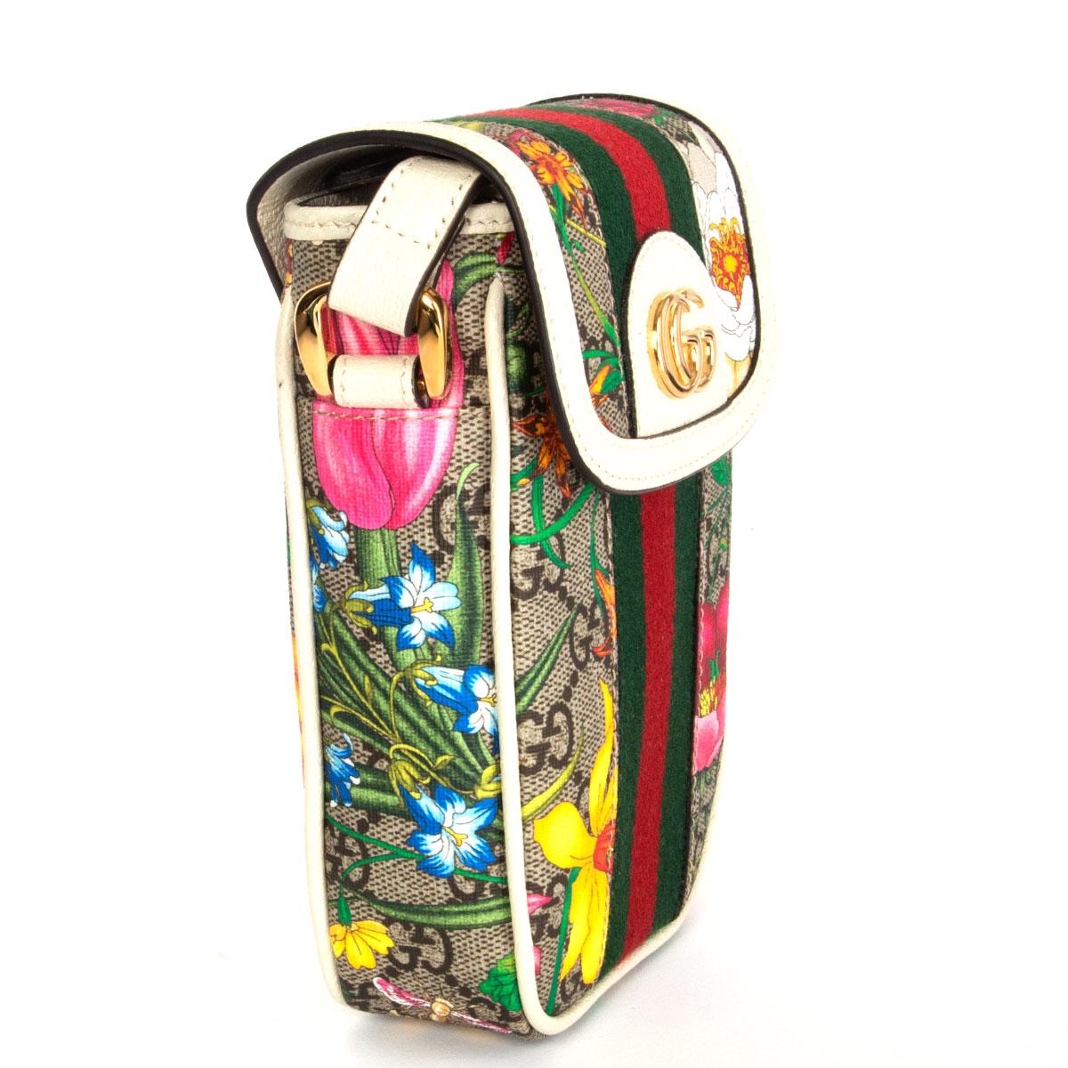 Gucci Ophidia mini phone bag in white leather and multicolored Floral GG Supreme canvas. Features an adjustable shoulder strap, a fold over front flap, a gold tone GG logo, a Web stripe down the front and an all-over Flora pattern. Has been carried