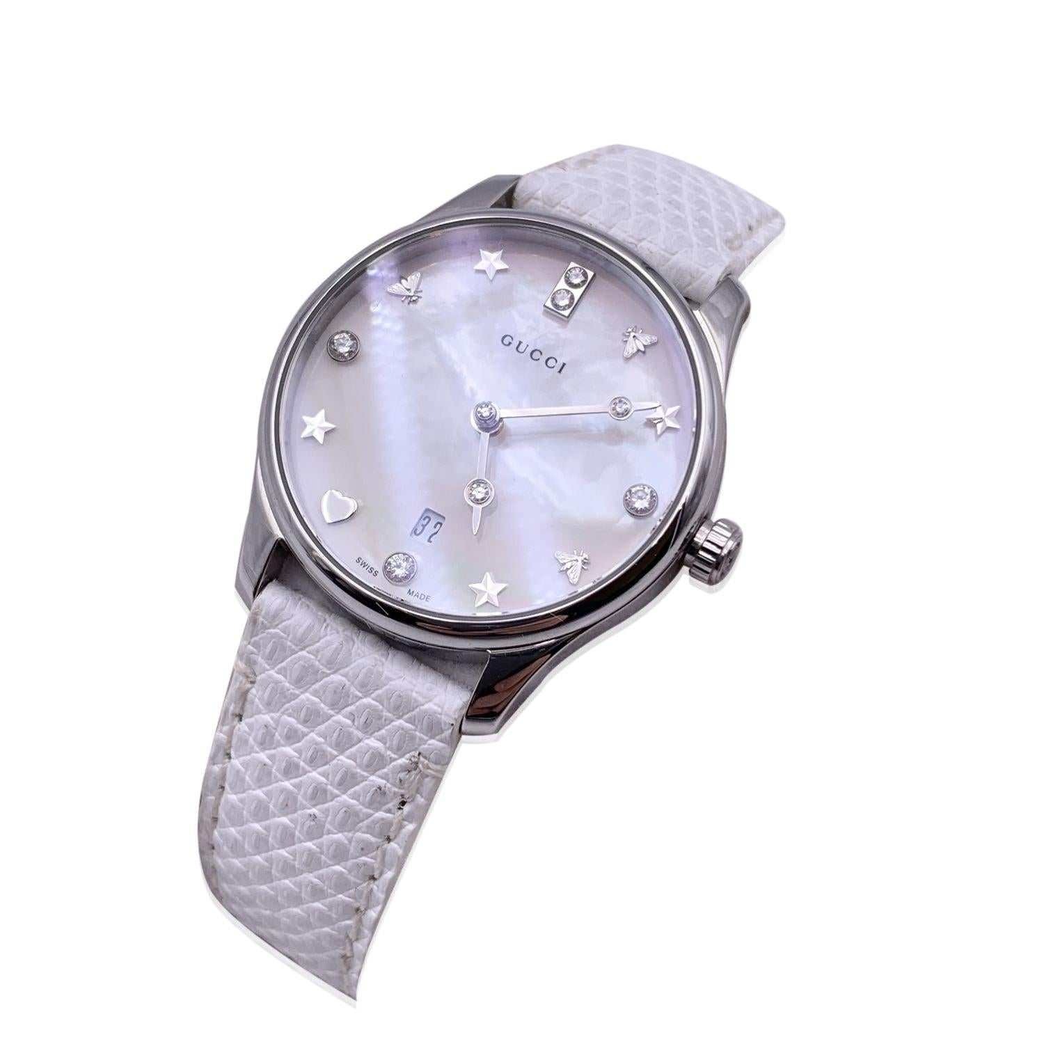 Gucci 'G-Timeless Slim' stainless steel watch. Model 126.5. Round stainless steel metal case (28 mm - crown included). White mother of pearl dial with date function. This watch feature diamonds, bees and stars motif hour markers. Two silver metal