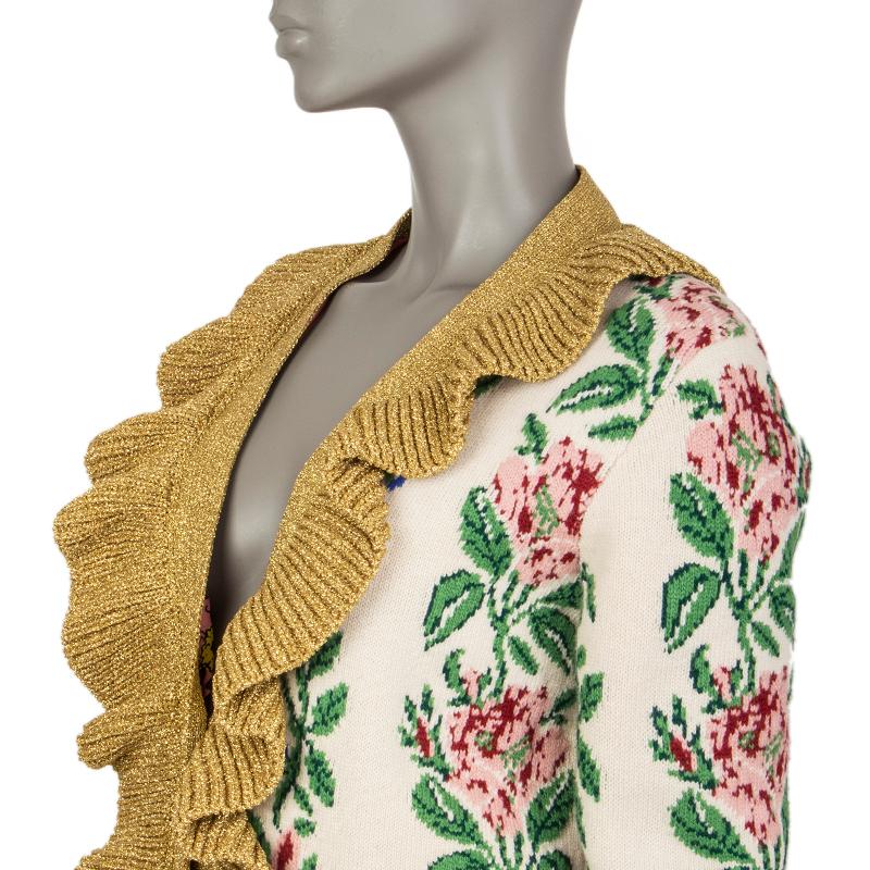 Gucci intarsia floral jacquard knit cardigan in cream, green, rose, magenta, blue, black, and gold wool (100%), metal fibers (54%), and nylon (48%). With ruffled collar, ribbed details and two pockets on the front. Closes with nacre buttons on the