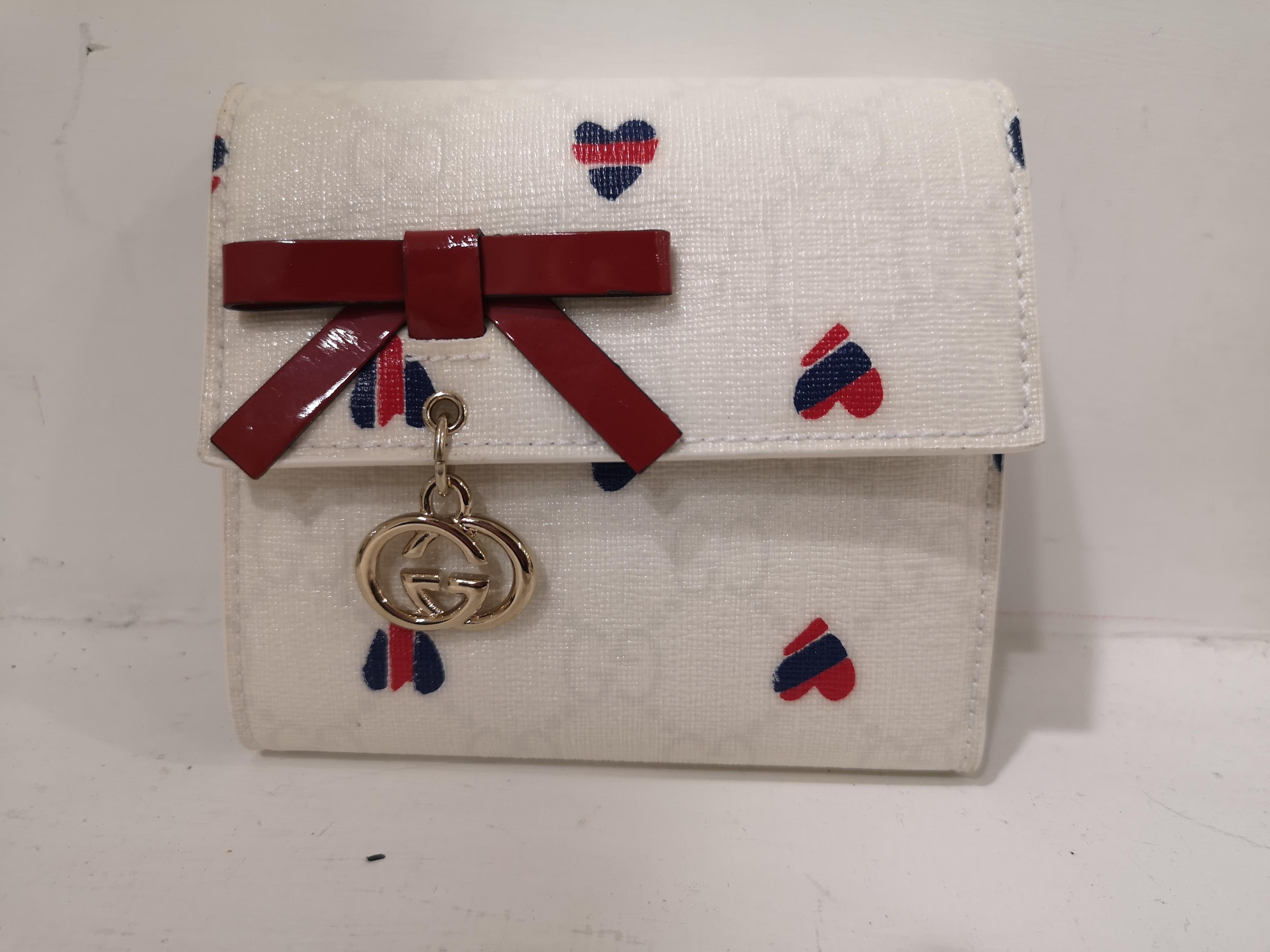 Gucci white heart wallet NWOT
Gucci white leather red and blue hearts wallet embellished on the front with a red patent bow 
still with dust and box
measurements:  11 * 11 cm