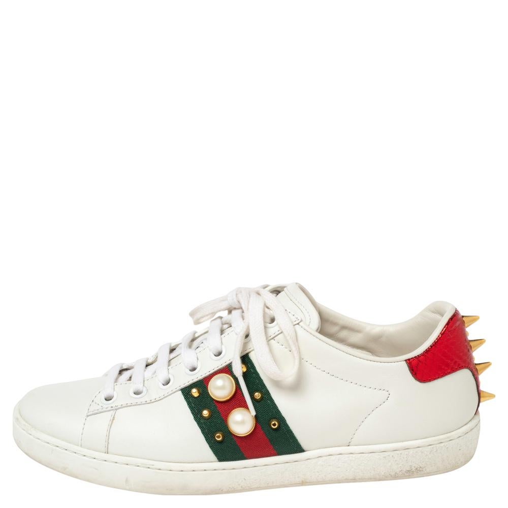 Stacked with signature details, this Gucci pair is rendered in leather and is designed in a low-cut style with lace-up vamps. They have been fashioned with the iconic web stripes, studs, and faux pearls on the sides. Complete with red and green