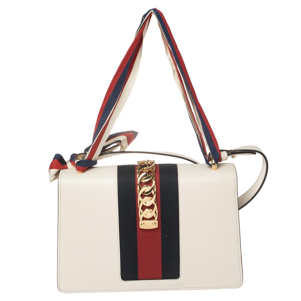 From the house of Gucci comes this gorgeous Sylvie shoulder bag that will perfectly complement all your outfits. It has been luxuriously crafted from white leather and styled with a chain-Web decorated flap and a buckle lock to secure the Alcantara