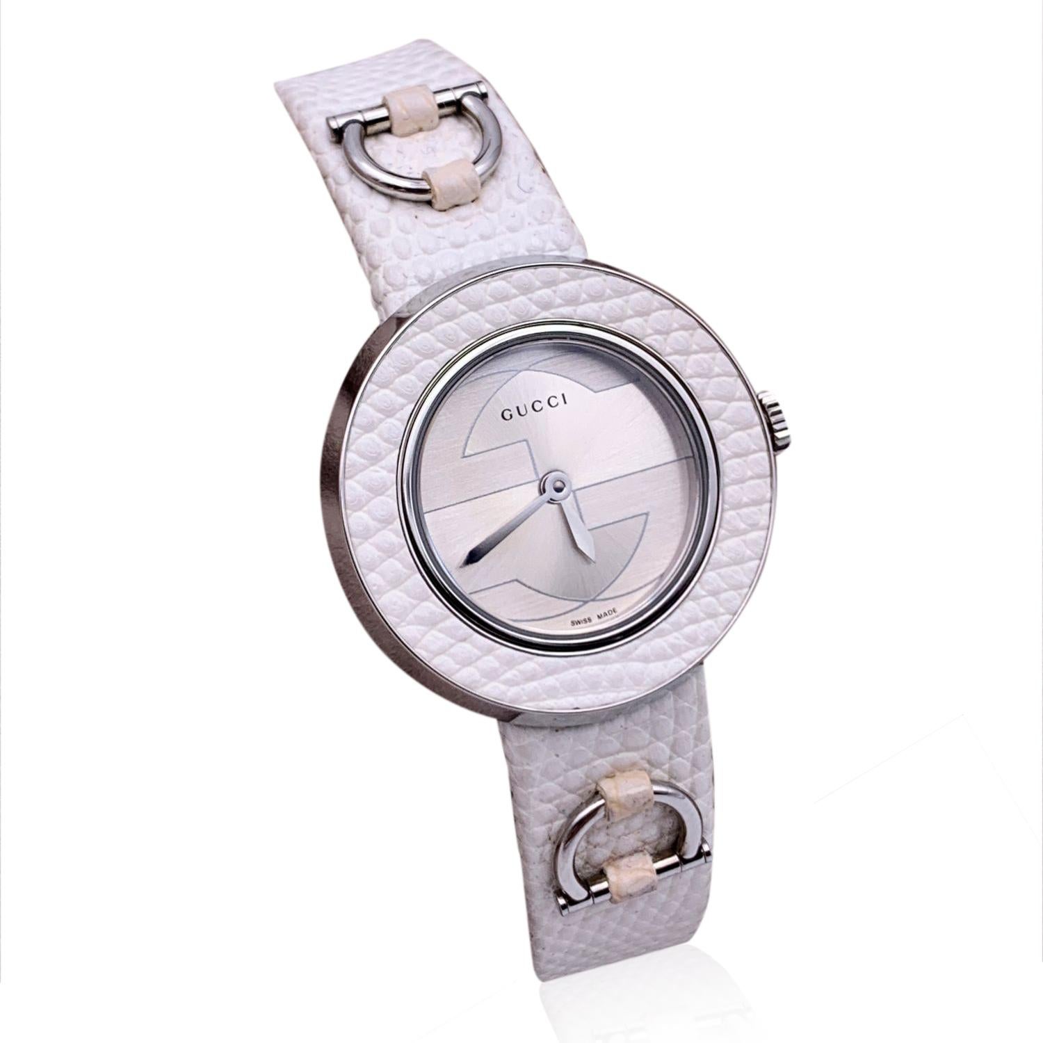 Gucci stainless steel watch. Mod. 129.5. Round case with GG logo on the dial and white leather bezel. Two hands. Sapphire crystal. Swiss Made Quartz movement. Gucci written on face. White leather strap. Adjustable strap. Water Resistant to 3 atm.