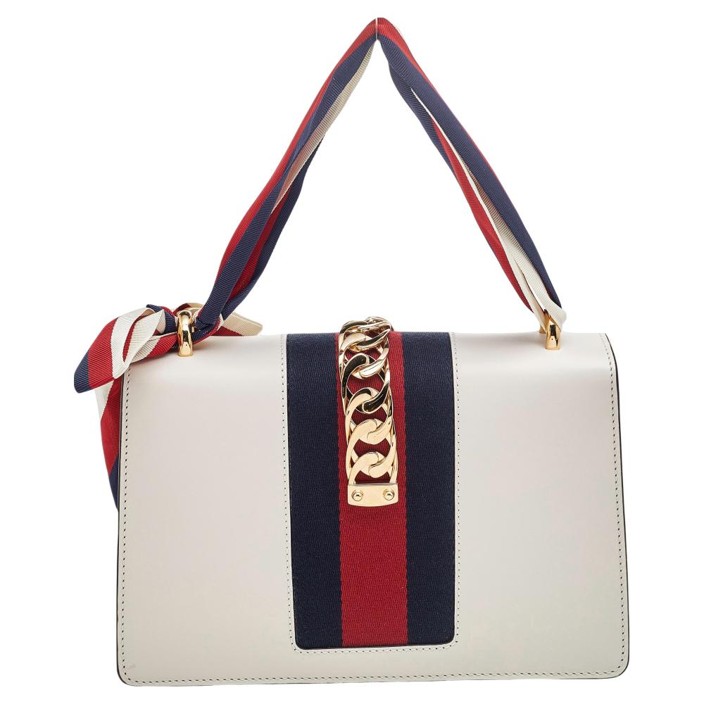 The gorgeous Gucci Sylvie shoulder bag will perfectly complement all your outfits. It has an elegant, structured silhouette highlighted by a decorative trim on the flap. The interior is sized well and two different handles are provided for easy