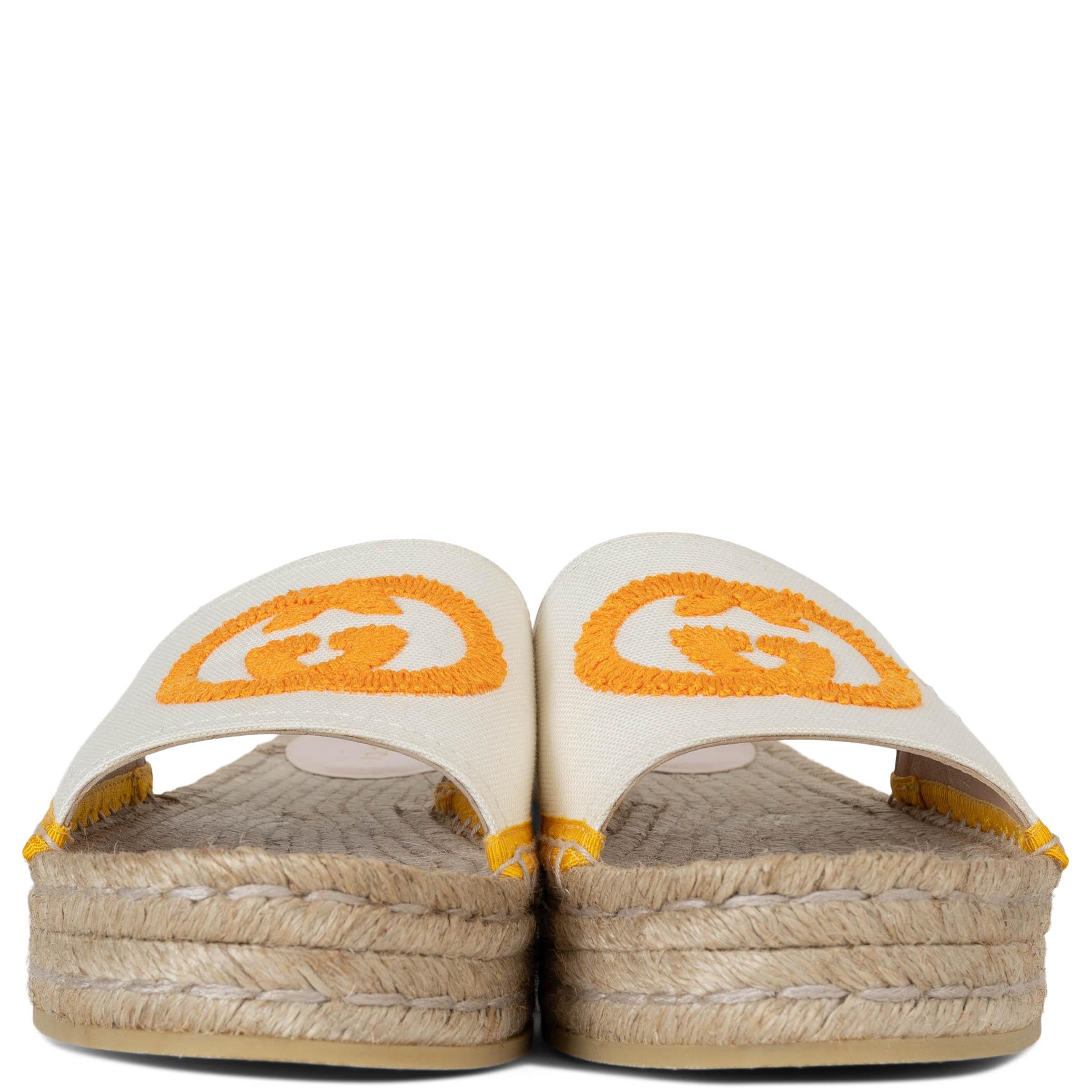 This 100% authentic Gucci Pilar slide sandals in white canvas with orange embroidered GG offer a fresh take on classic espadrilles. Designed with a platform sole and yellow grosgrain trim, they blend casual elegance with a hint of vintage charm. The