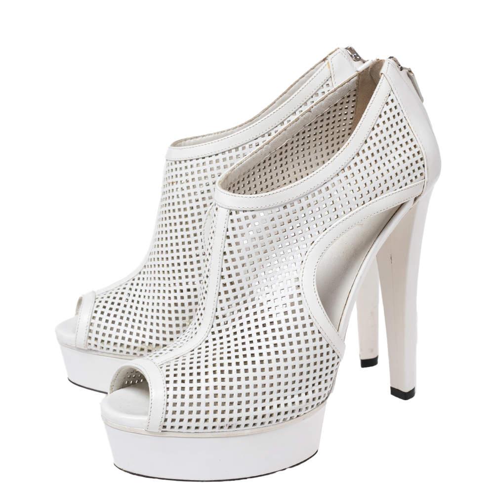 An exceptional flair and a chic appeal characterize these stunning Kim booties from Gucci. They are designed using white perforated leather into an ankle-length structure. They showcase peep-toes, platforms, and 13.5 cm heels. Elevate the look of