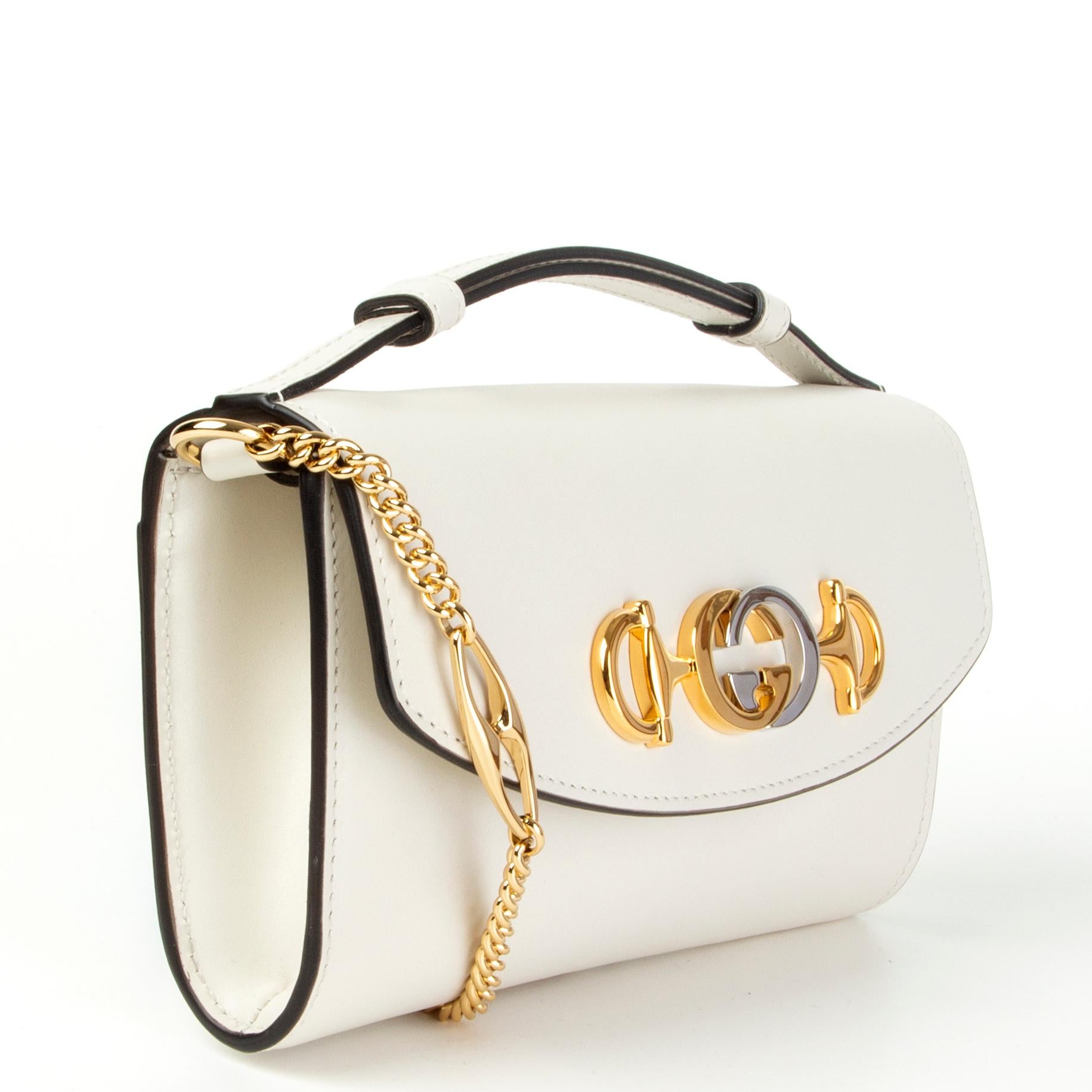 Gucci 'Zumi' mini bag in off-white smooth leather featuring interlocking GG horsebit in silver- and gold-tone metal. Open pocket on the back and detachable gold-tone metal chain shoulder strap. Opens with a magnetic button under the flap and is