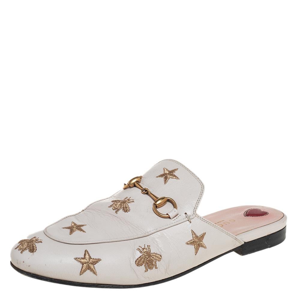 Diese Gucci Princetown Pantoletten sind ein frisches Update der immer wieder schicken Gucci Loafers. Sie werden durch die charakteristischen Horsebit-Beschläge sowie Stern- und Bienenmotive veredelt:: die die Gucci-Kollektion seit jeher auszeichnen.