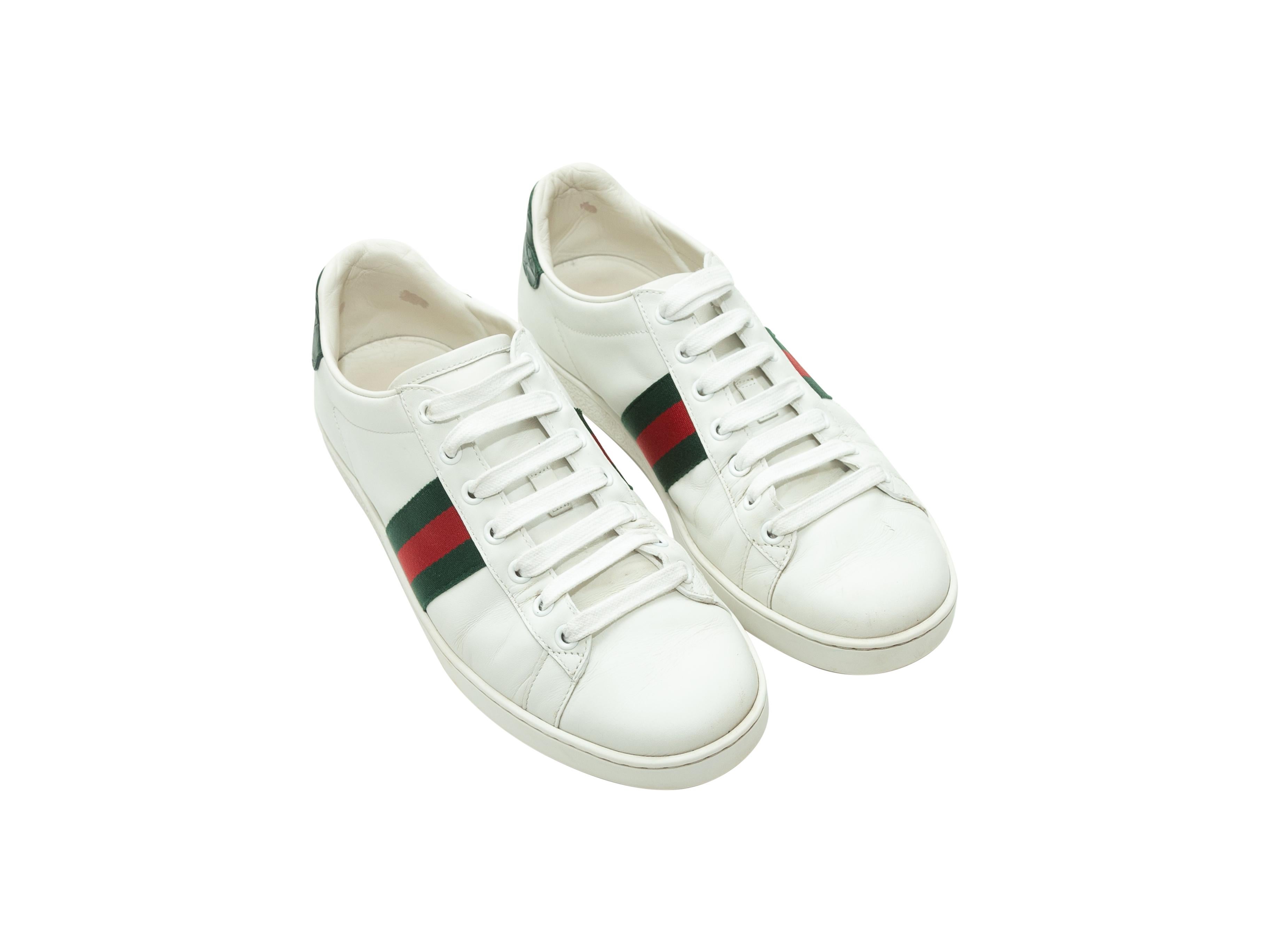Product details: White leather low-top sneakers by Gucci. Green and red Gucci Web trim at sides. Crocodile accent panels at backs. Lace-up tie closures at tops. Designer size 40.
Condition: Pre-owned. Good. Scuffing at leather. Marks and wear at