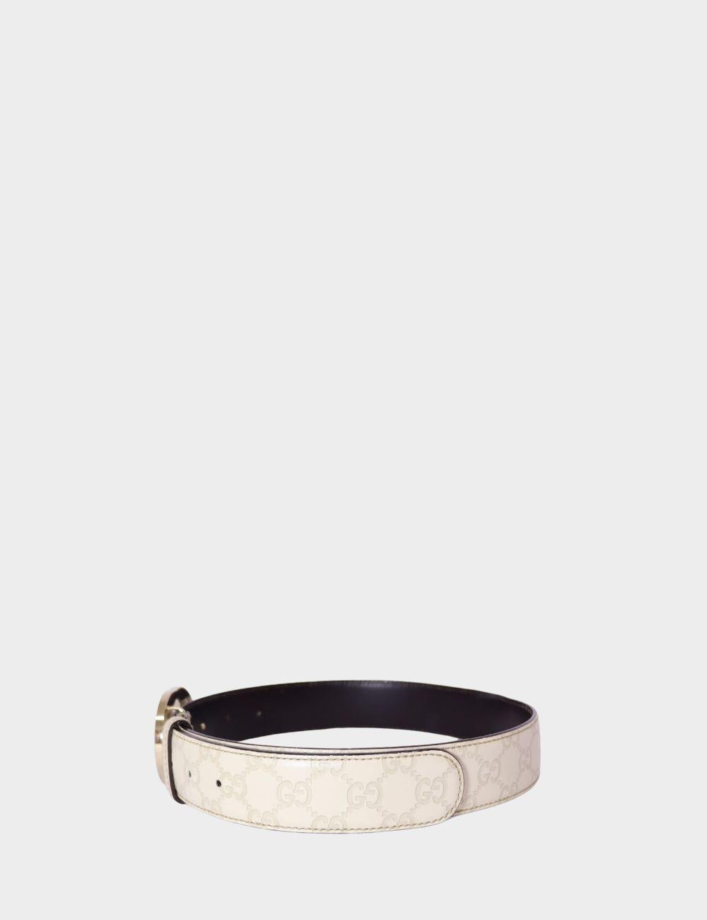 Complete your look with this iconic Gucci white leather belt, featuring the signature GG monogram embossed pattern. This statement accessory is finished with a bold silver-tone double G buckle, showcasing Gucci's timeless luxury aesthetic. Crafted