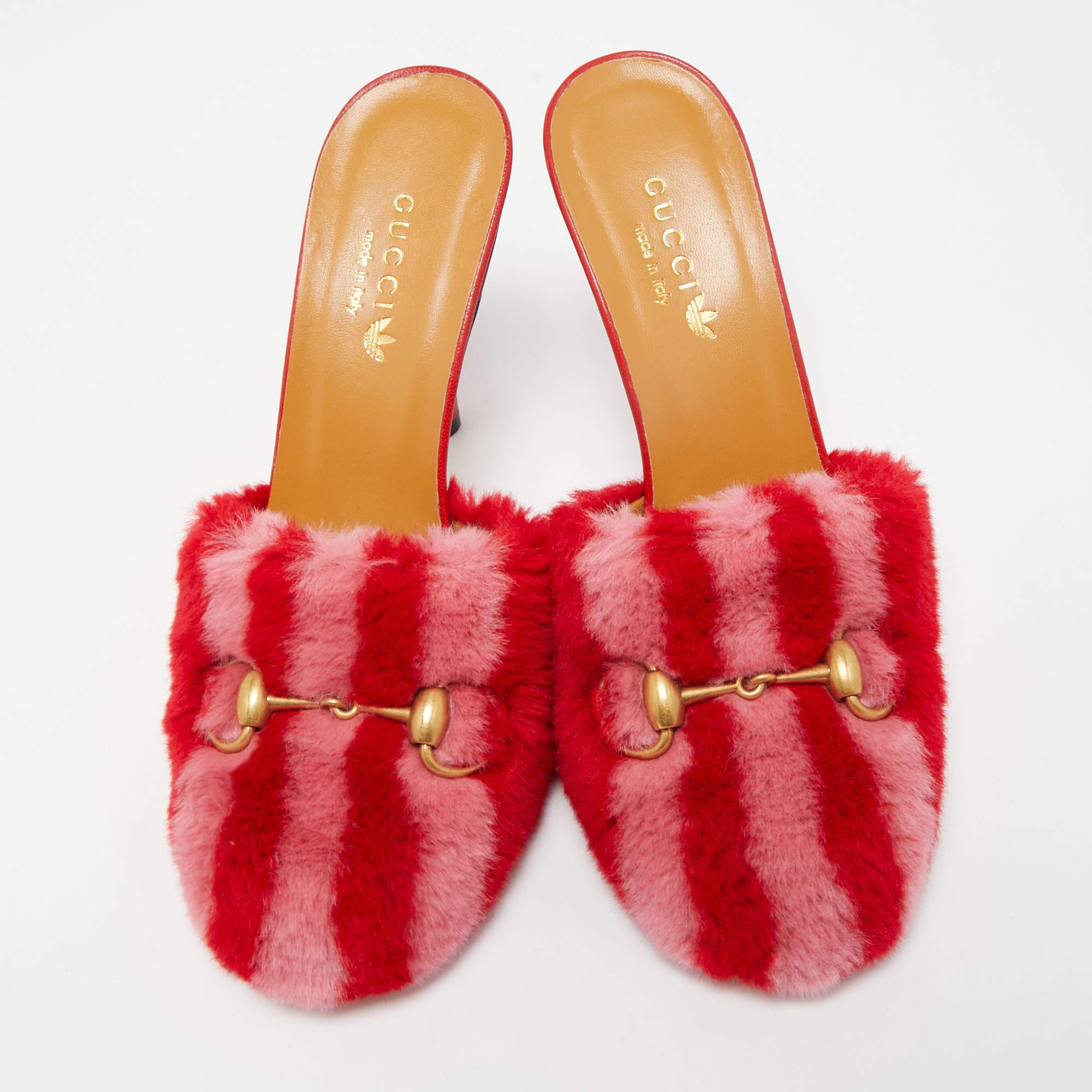 The Gucci x Adidas Red/Pink Shearling Fur Horsebit Mules are a luxurious blend of fashion and comfort. These stylish mules feature a striking red and pink color scheme, adorned with the iconic Horsebit detail. The soft, shearling fur lining adds