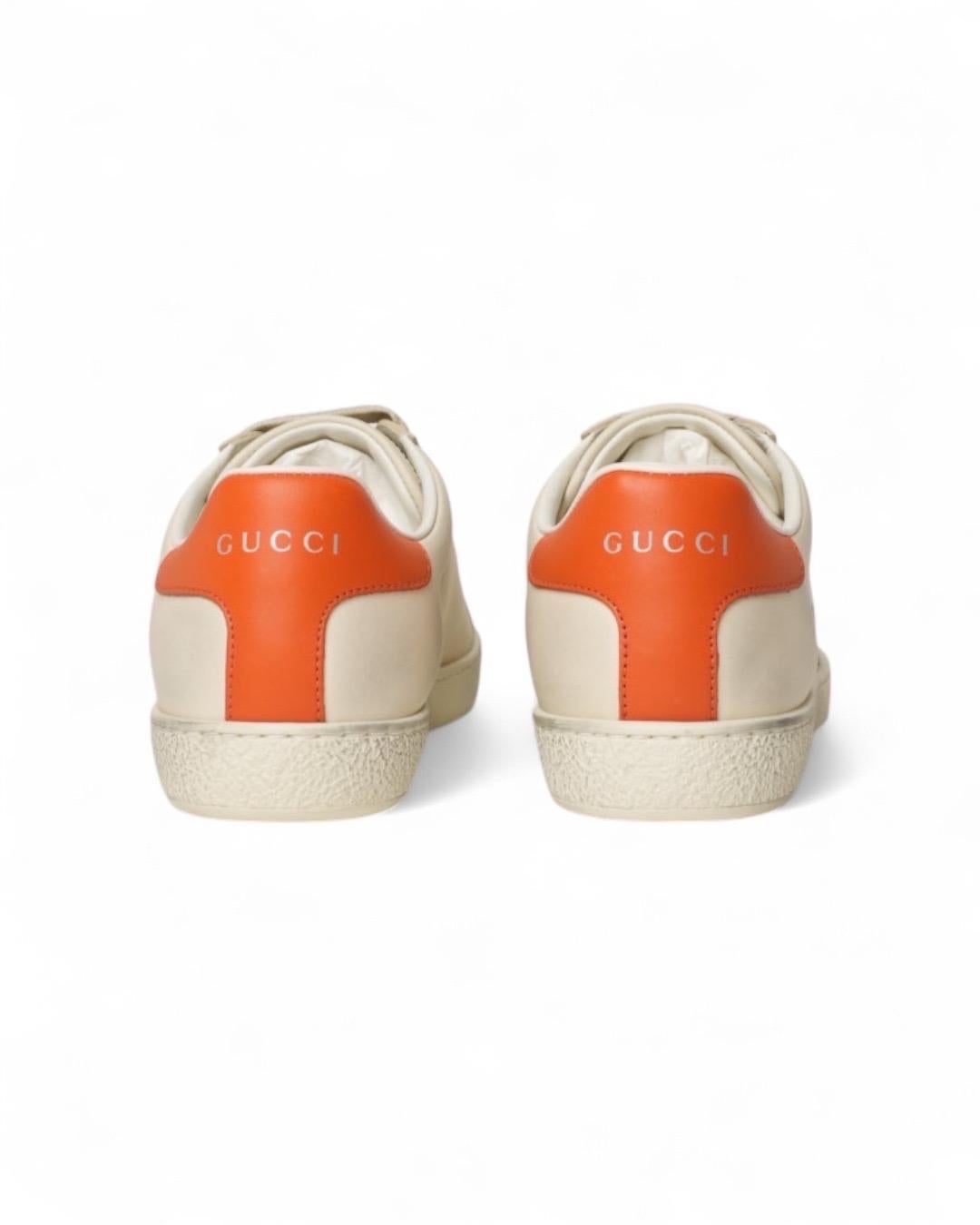 Sneakers firmate Gucci, in collaborazione con Disney, realizzate in PELLE avorio con rifiniture arancioni e arricchite dalla stampa di topolino sul lato. Munite di una chiusura con lacci e suola in gomma. Numero 36 e mezzo. L'articolo si presenta in